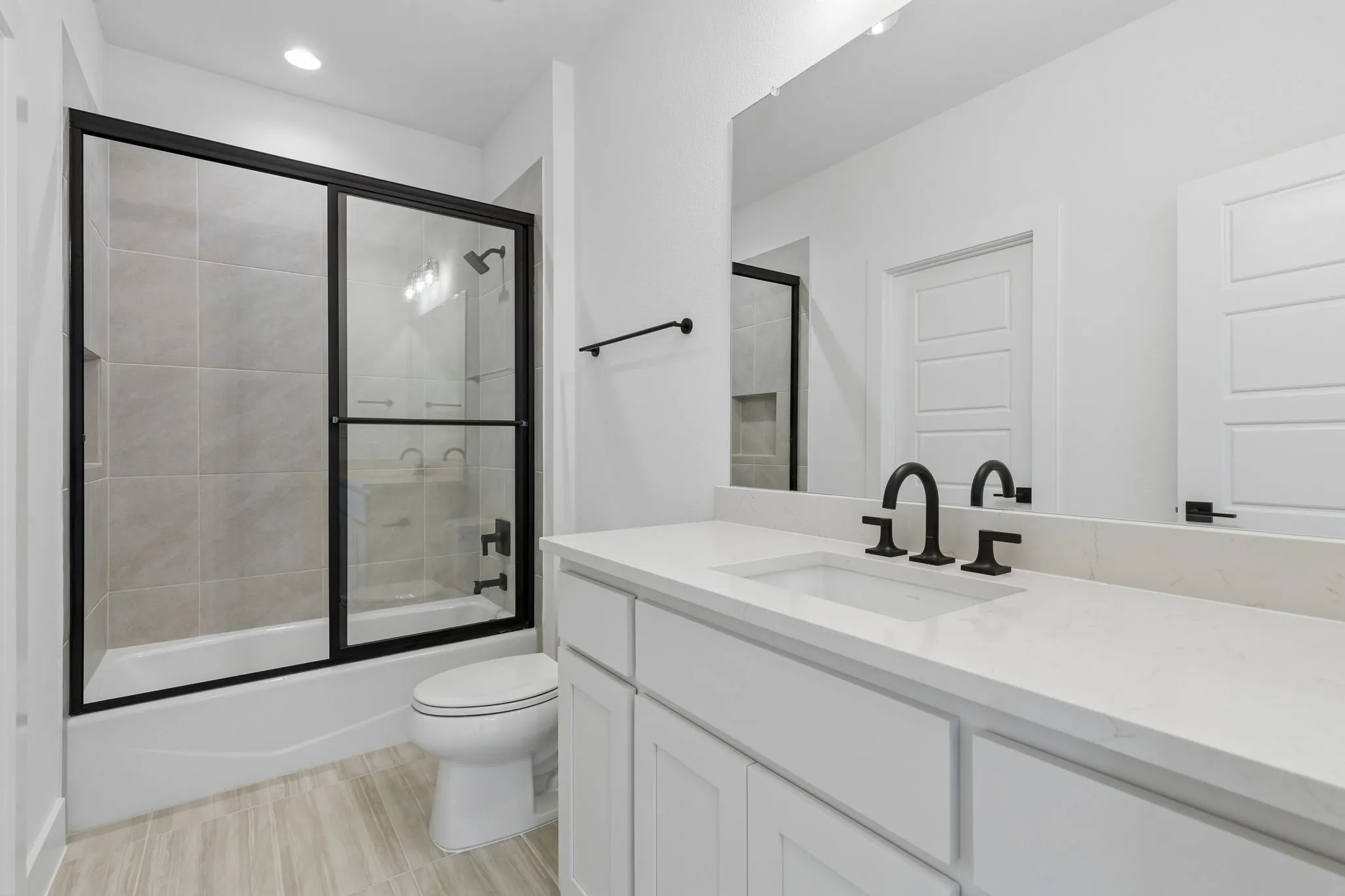 White vanity with a light-toned countertop, rectangular undermount sink, and matte black fixtures