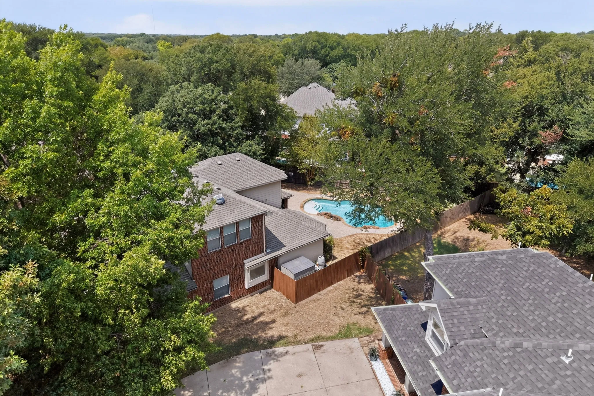 Brick exterior, multi-story structure, fenced property, backyard swimming pool, mature trees