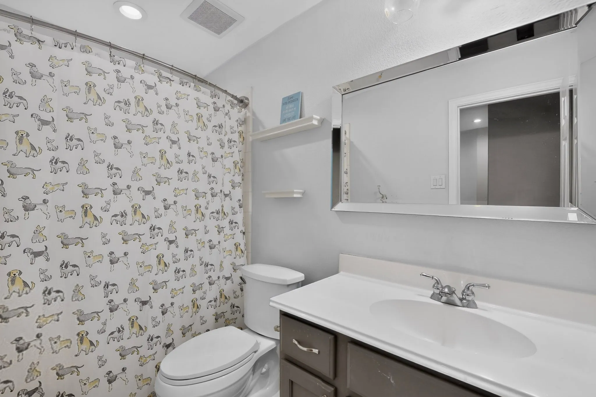Vanity with integrated sink and brushed nickel faucet, framed mirror, built-in shelving, and recessed lighting