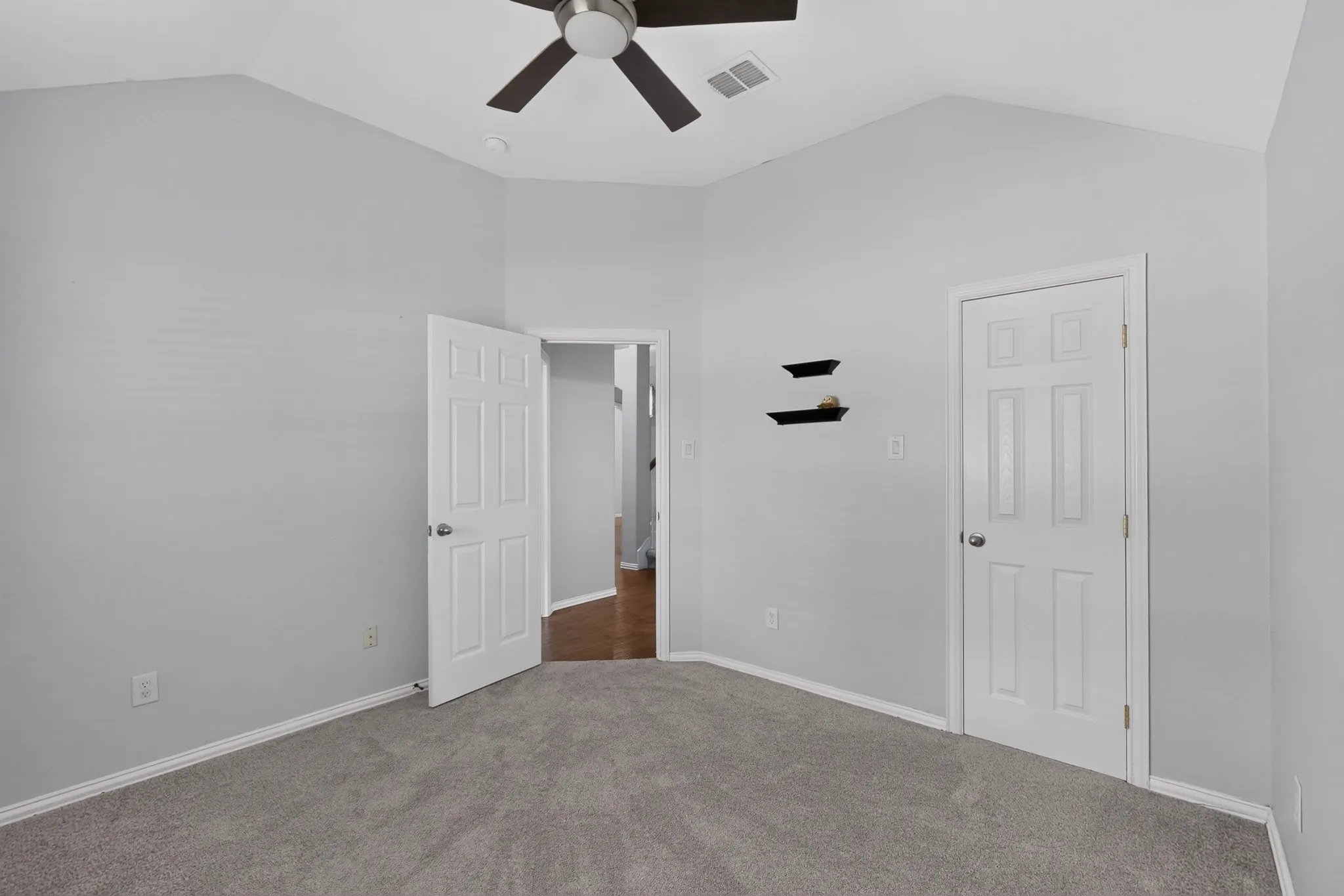 Vaulted ceiling with a ceiling fan, light gray wall paint, and gray carpet flooring