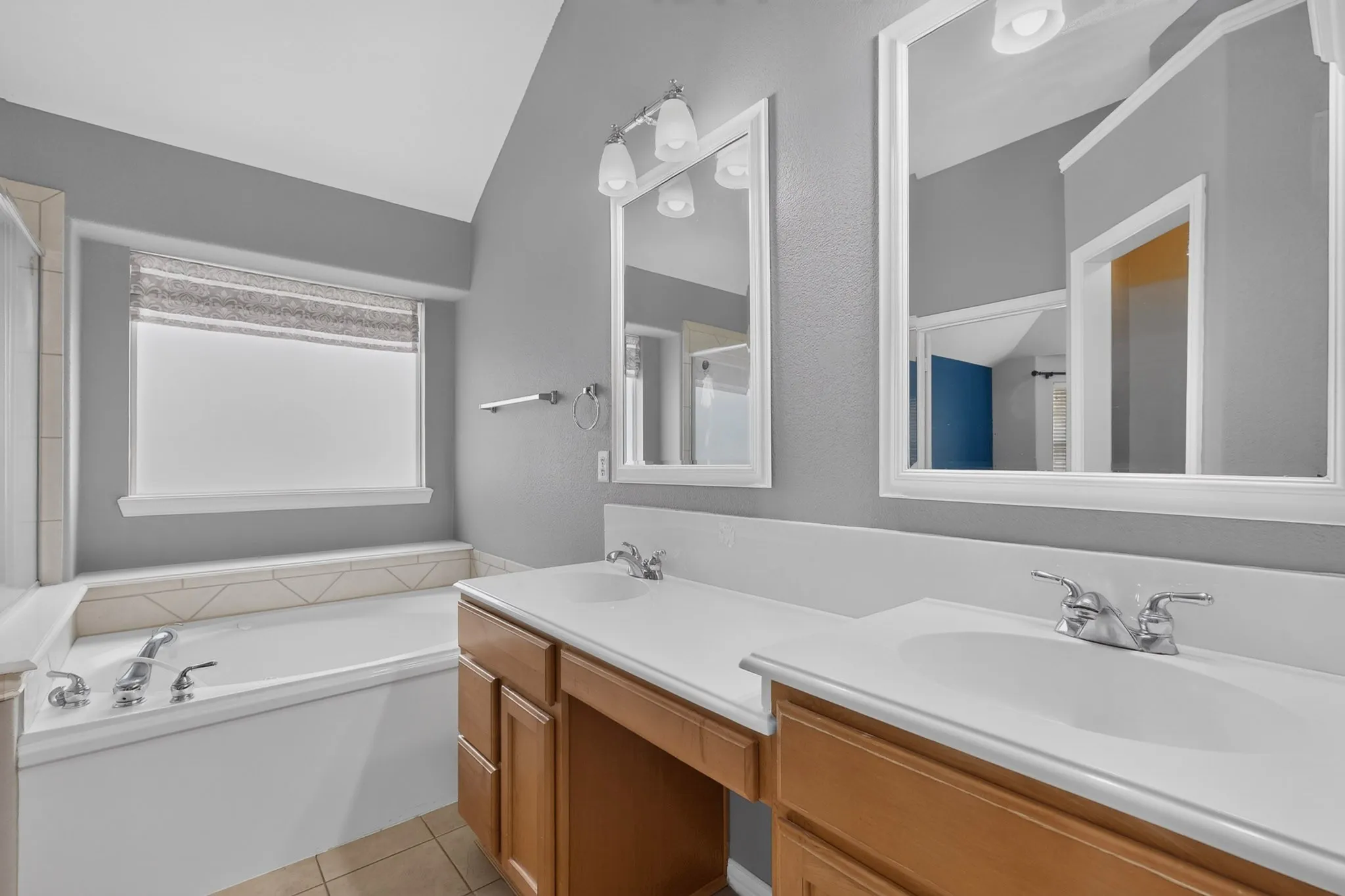 Dual vanity with individual sinks, integrated bathtub with tiled surround, and ceramic tile flooring