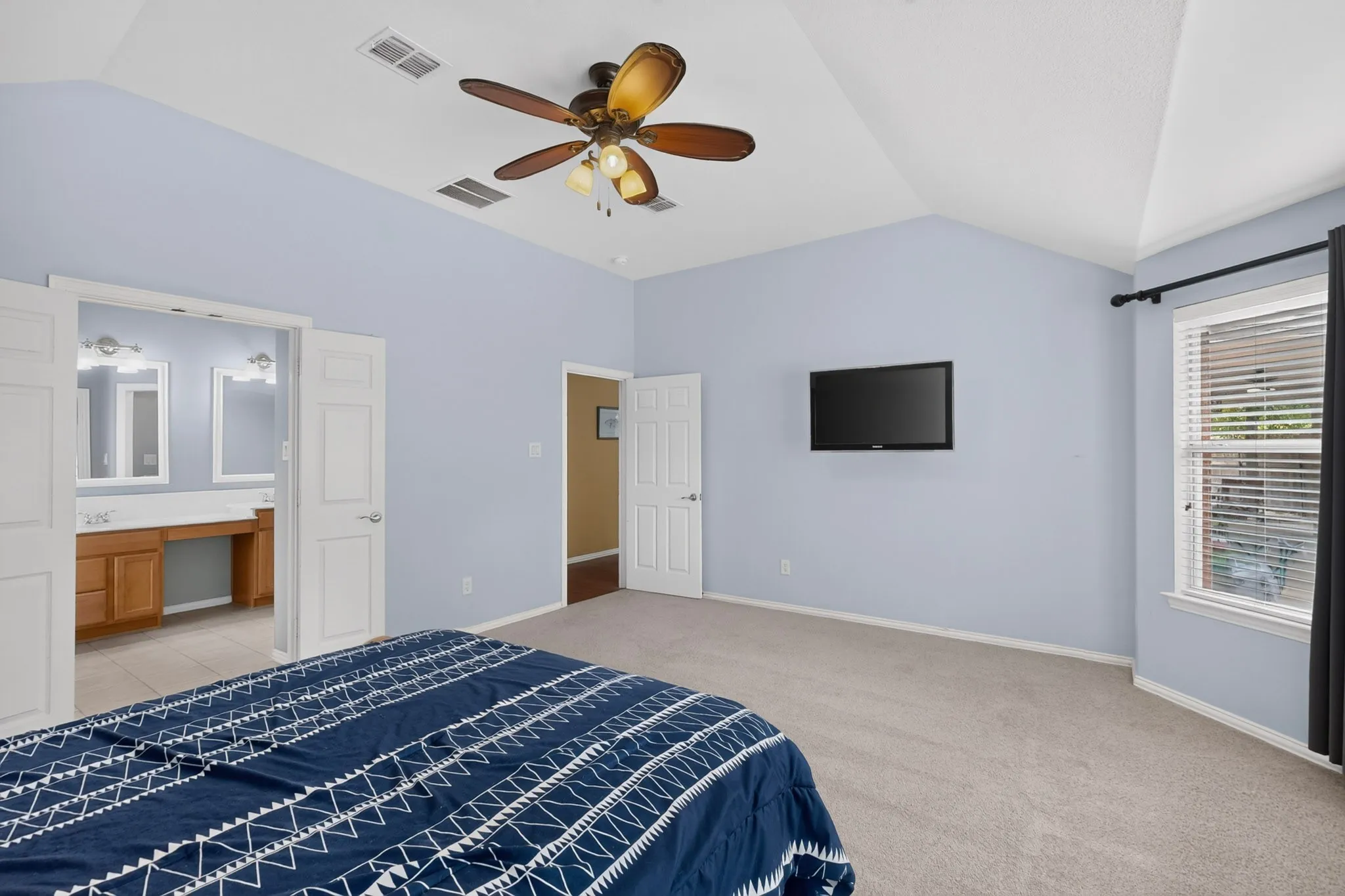 Vaulted ceiling with a ceiling fan, carpet flooring, window with blinds, and a private vanity area