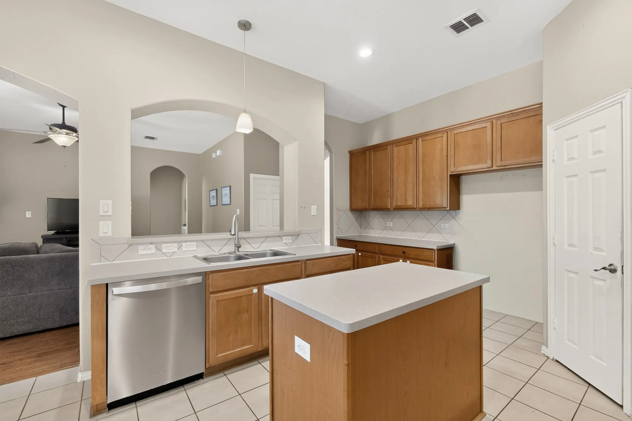Kitchen featuring a central island, wood cabinetry, stainless steel dishwasher, and tile flooring