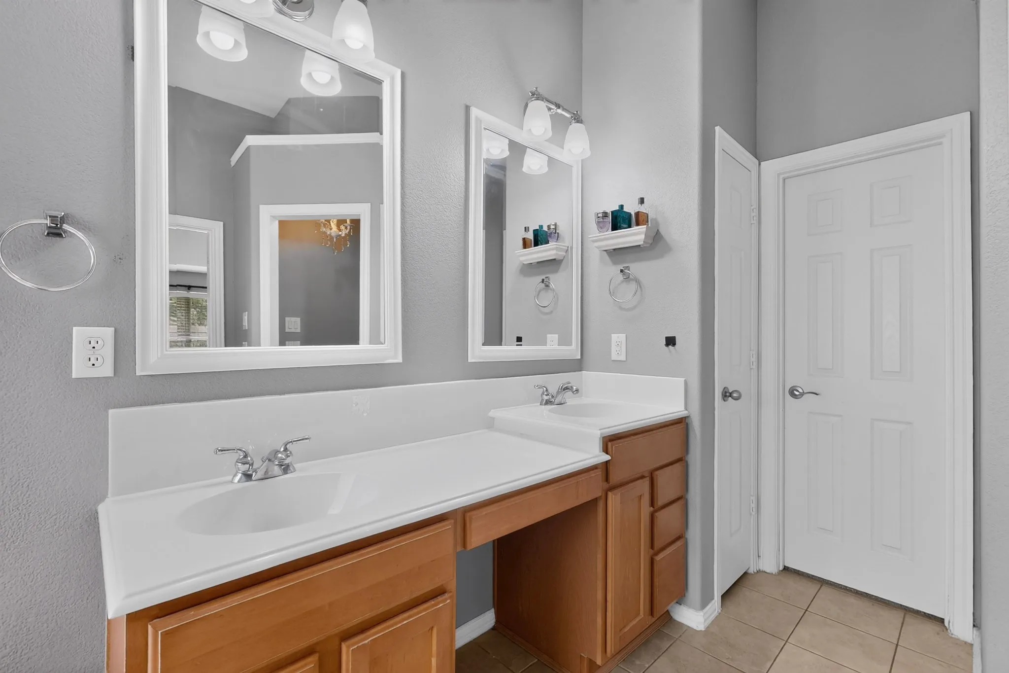 Dual vanity with wood-finish cabinetry, integrated sinks, chrome faucets, and framed mirrors