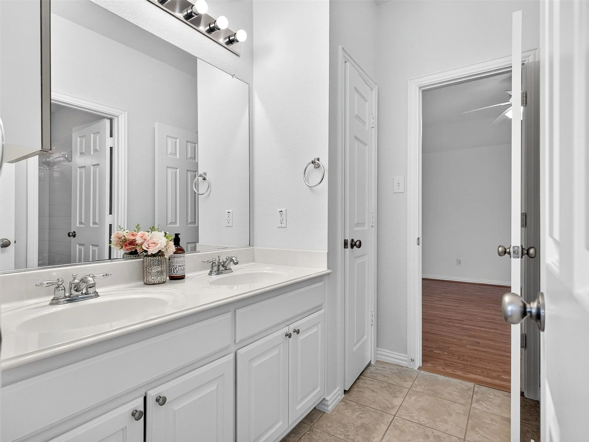 Double vanity with white cabinetry, dual undermount sinks, and polished chrome faucets