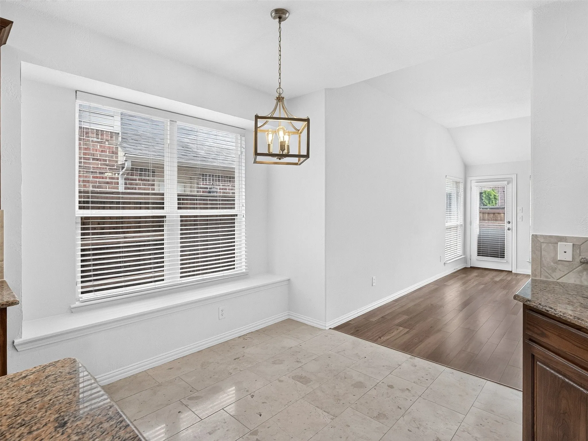 Large window with an integrated window seat, pendant lighting, wood-finish flooring, and tile flooring