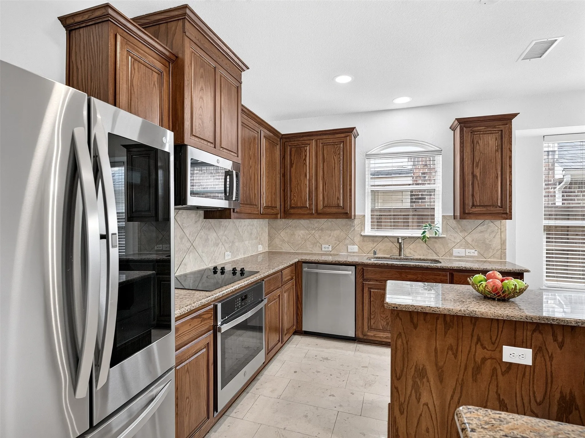 Kitchen featuring wood cabinetry, stainless steel appliances, tile flooring, and stone countertops