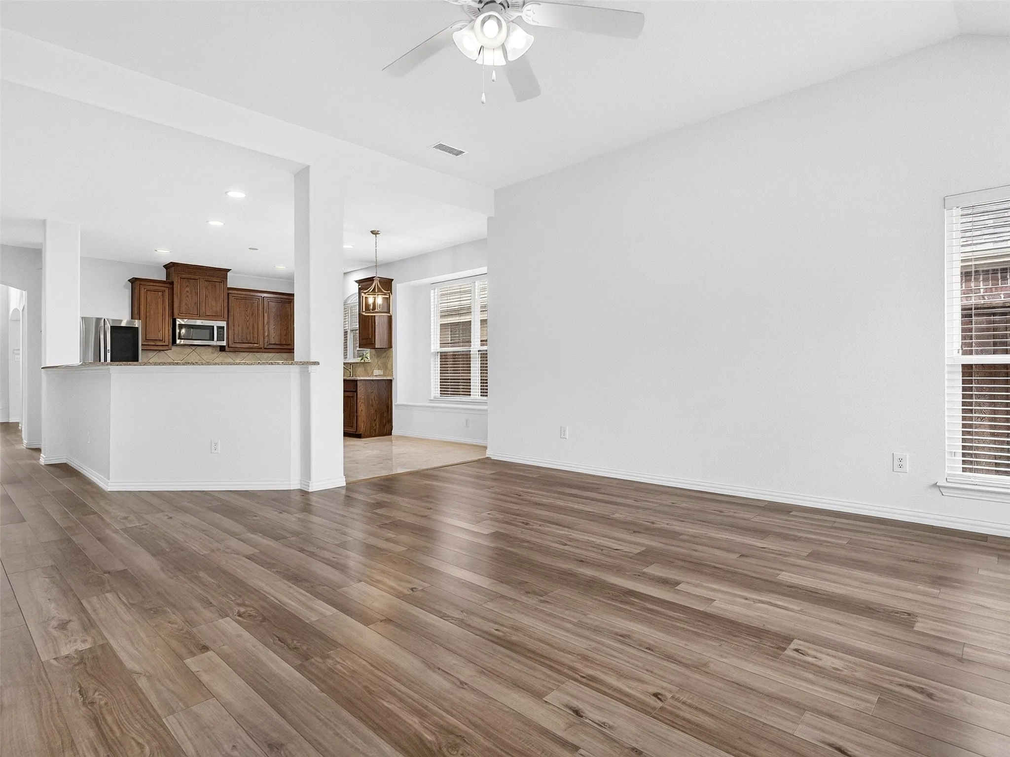 Wood-finish flooring throughout, white walls, and a ceiling fan