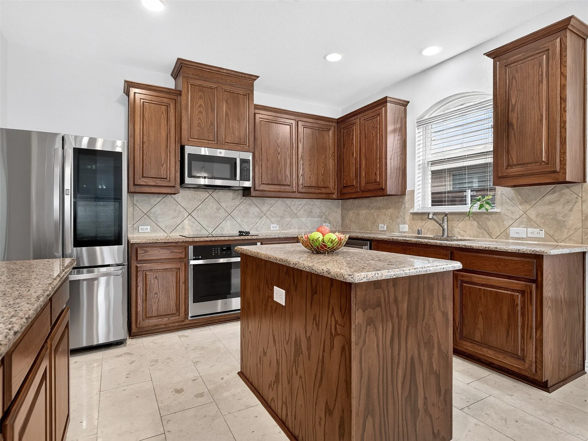 Kitchen featuring wood cabinetry, stainless steel appliances, a center island with a stone countertop, and tile flooring