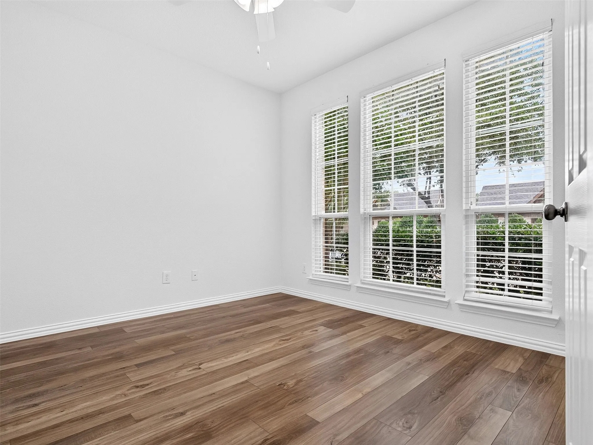 Wood-finish flooring, white walls, and a ceiling fan