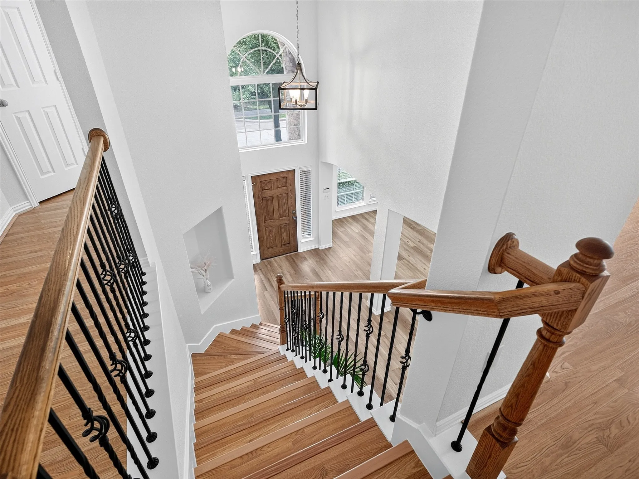 Grand entryway featuring a wood-panel door, arched transom window, and a chandelier