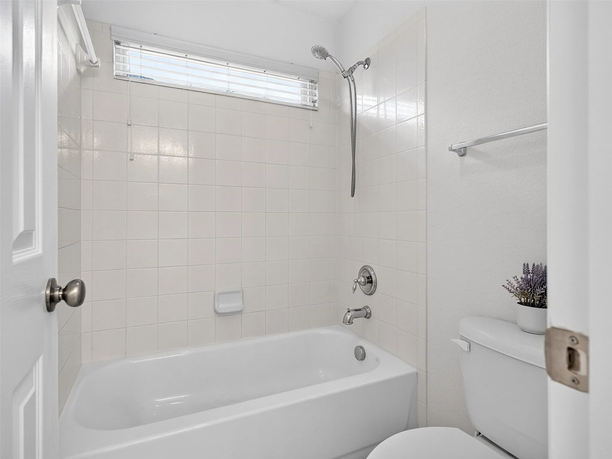Clean and bright bathroom featuring white subway tile walls, a soaking tub with chrome fixtures, a separate shower enclosure with handheld showerhead, and a transom window providing natural light