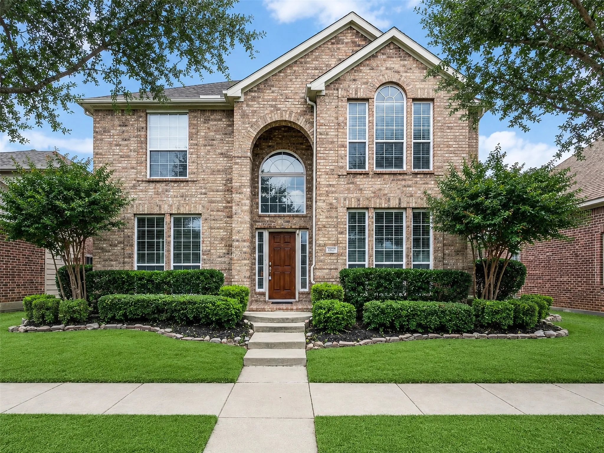 Brick exterior with prominent arched entryway, multiple gables, and a large arched window above the front door