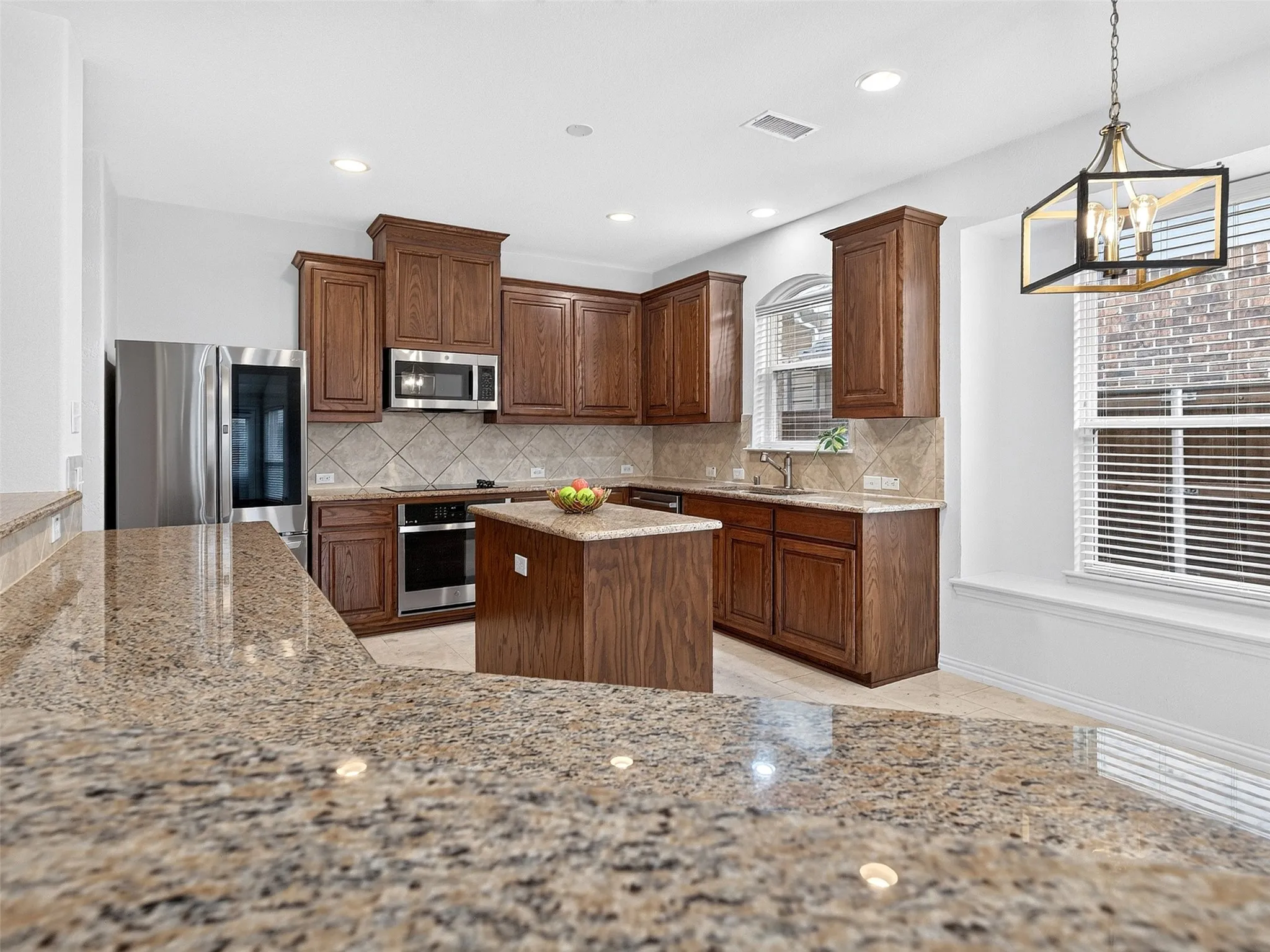 Kitchen featuring a central island, wood cabinetry, stone countertops, and stainless steel appliances