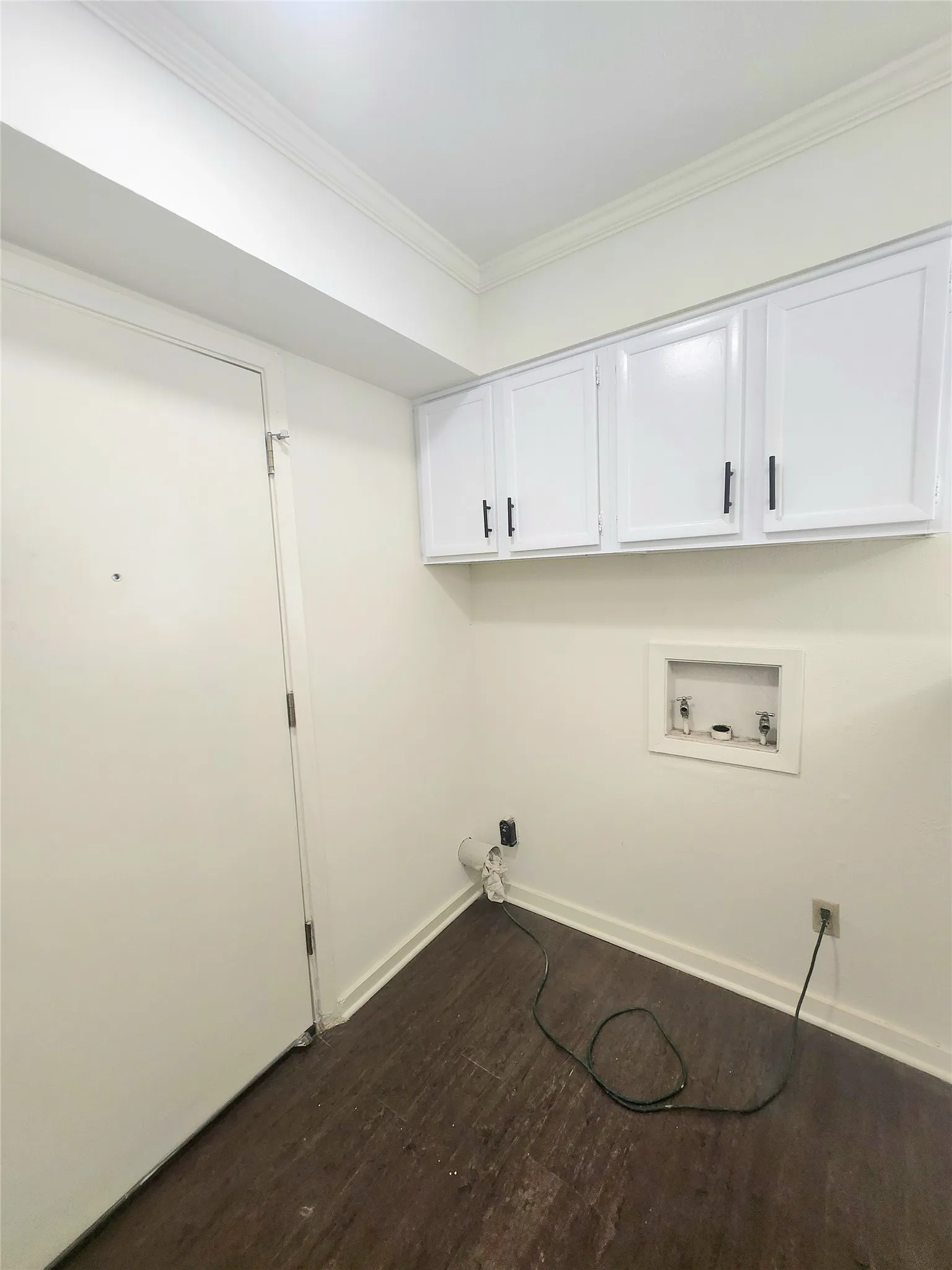 White wall cabinetry with black hardware, wood-finish flooring, and crown molding