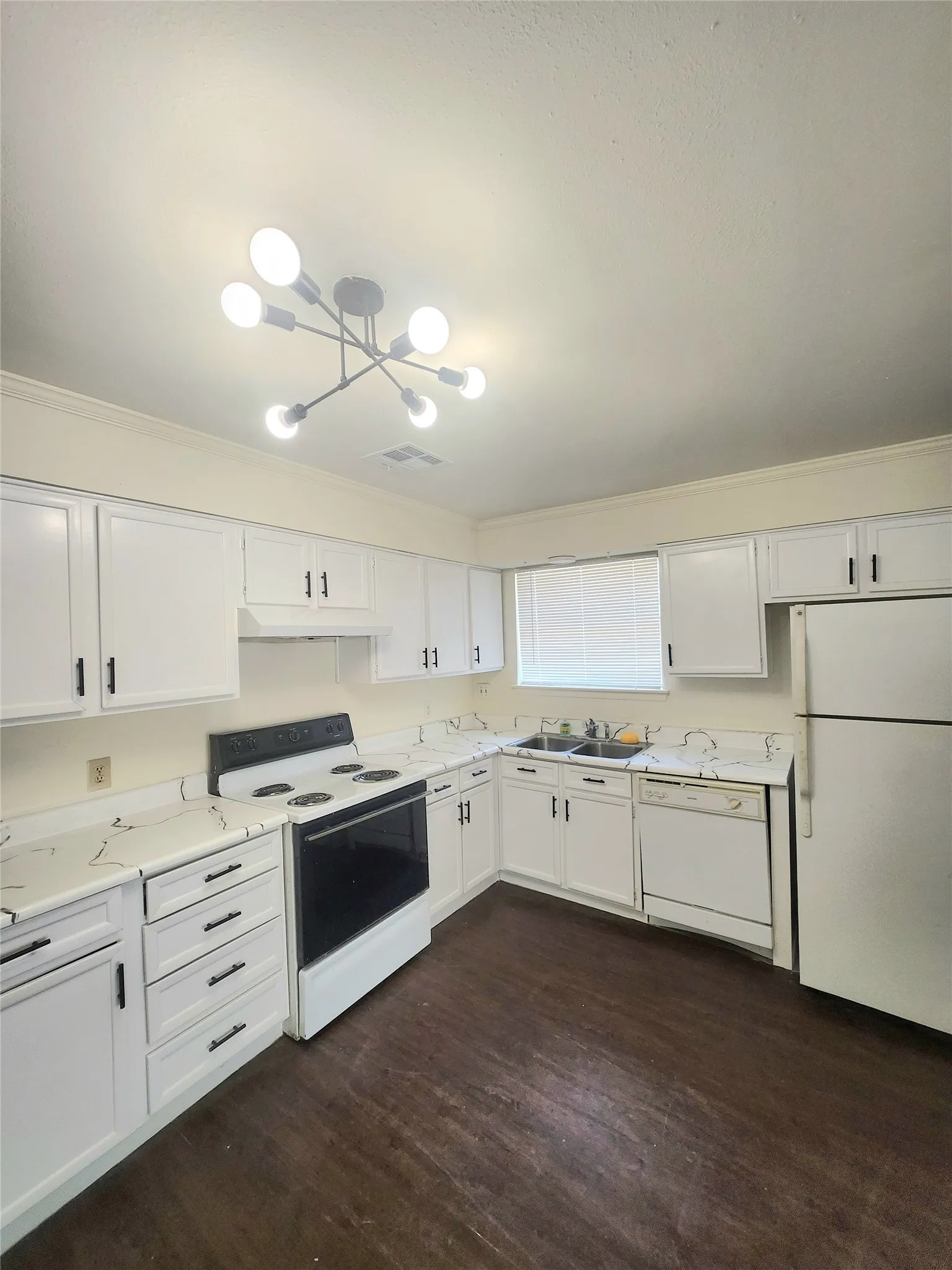 White cabinetry with black hardware, wood-finish flooring, white appliances, and a modern ceiling light fixture