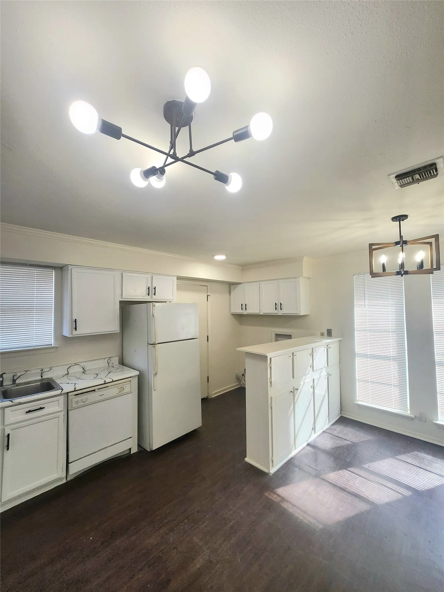 Kitchen featuring white cabinetry, dark wood-finish flooring, white appliances, and a breakfast bar