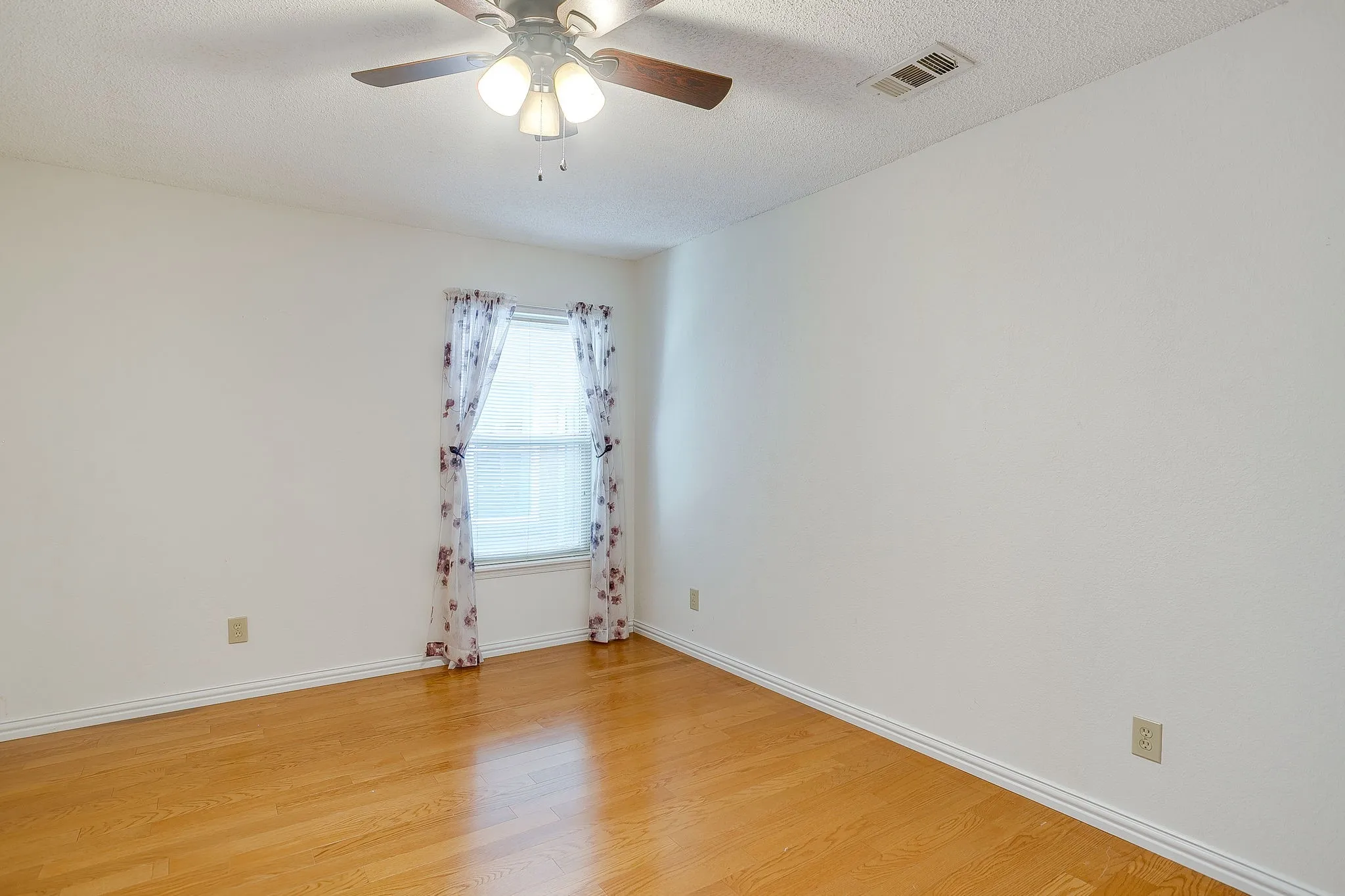 Secondary bedroom with wood flooring.