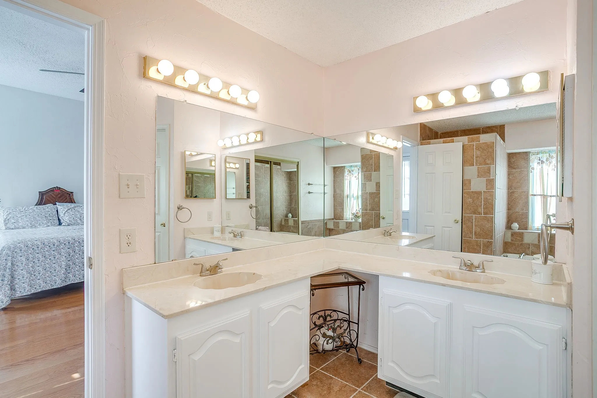 L-shaped dual-sink vanity with abundant counter space, and dedicated vanity lighting.