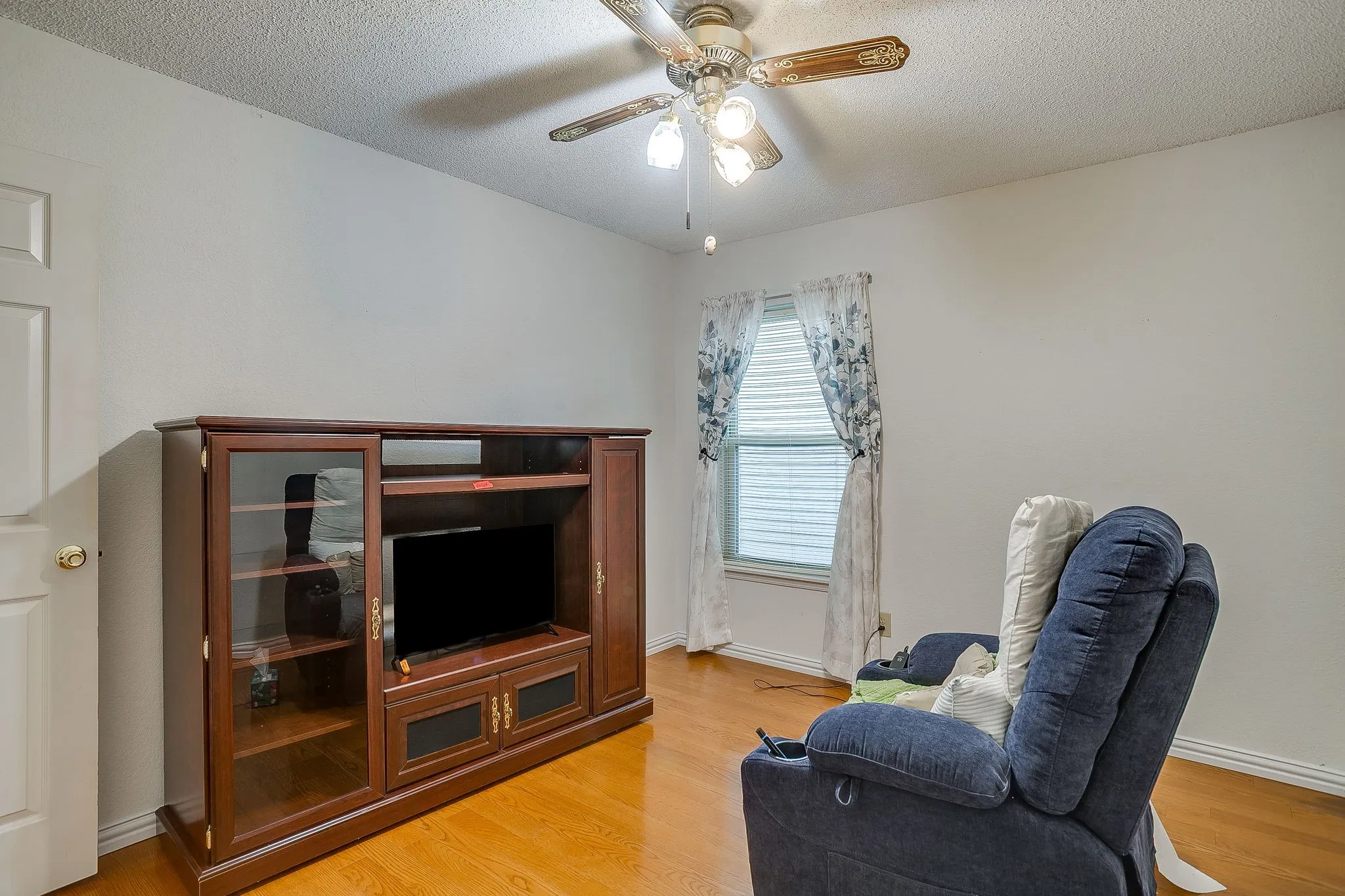 Secondary bedroom with wood flooring.