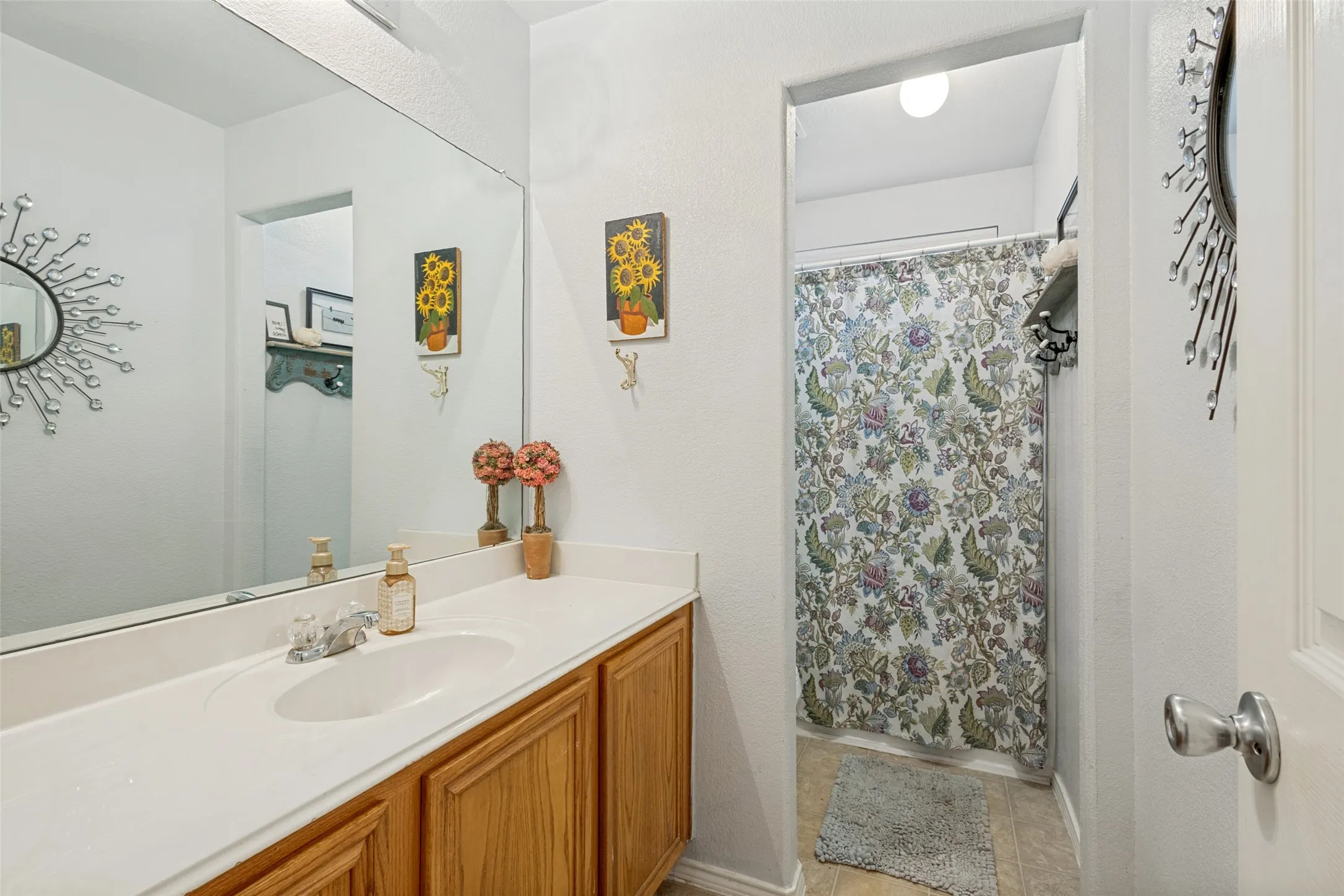 White vanity with a built-in sink, chrome faucet, and wood-finish cabinetry