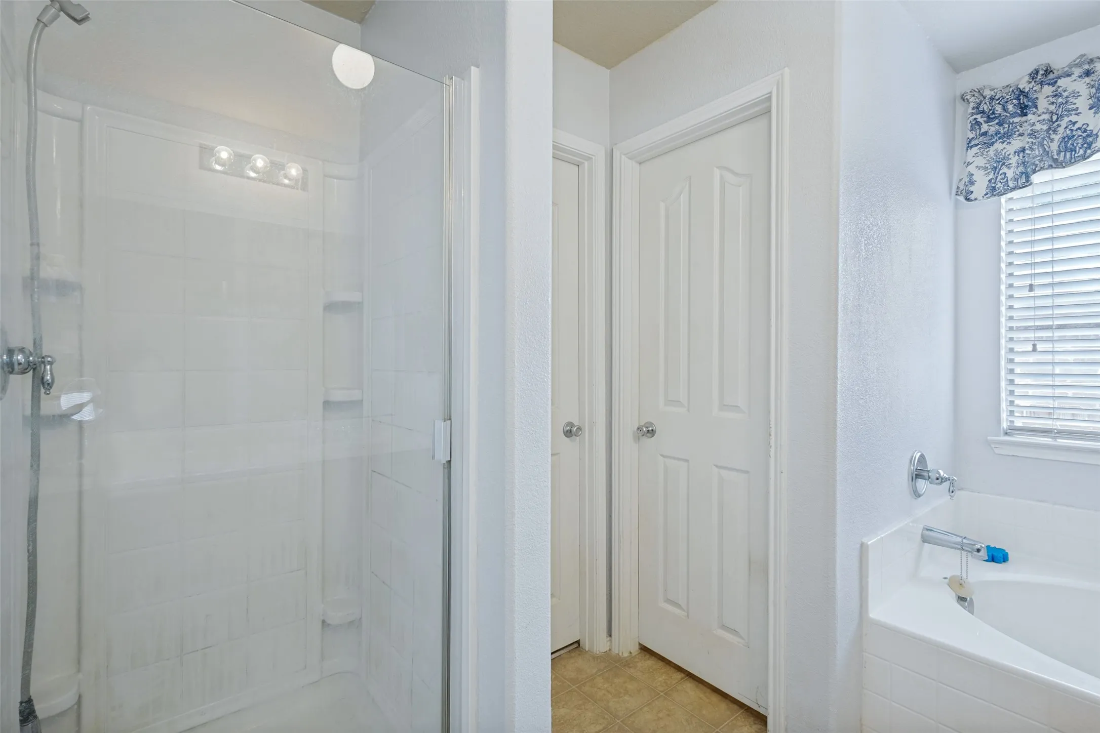 Shower enclosure with clear glass door, tile surround, and built-in shelving