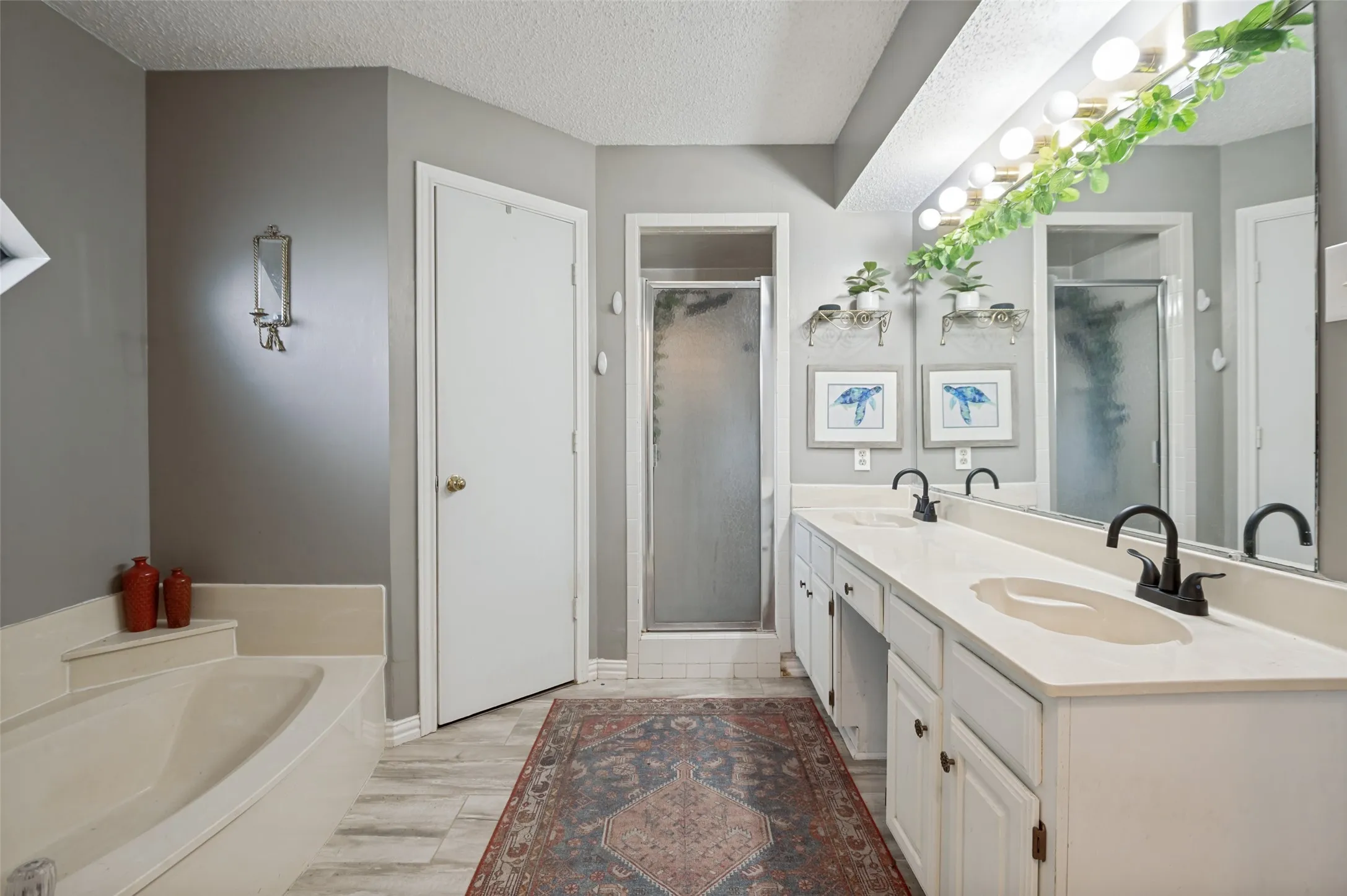 Built-in bathtub, double vanity countertop, matte black faucets, and separate shower enclosure