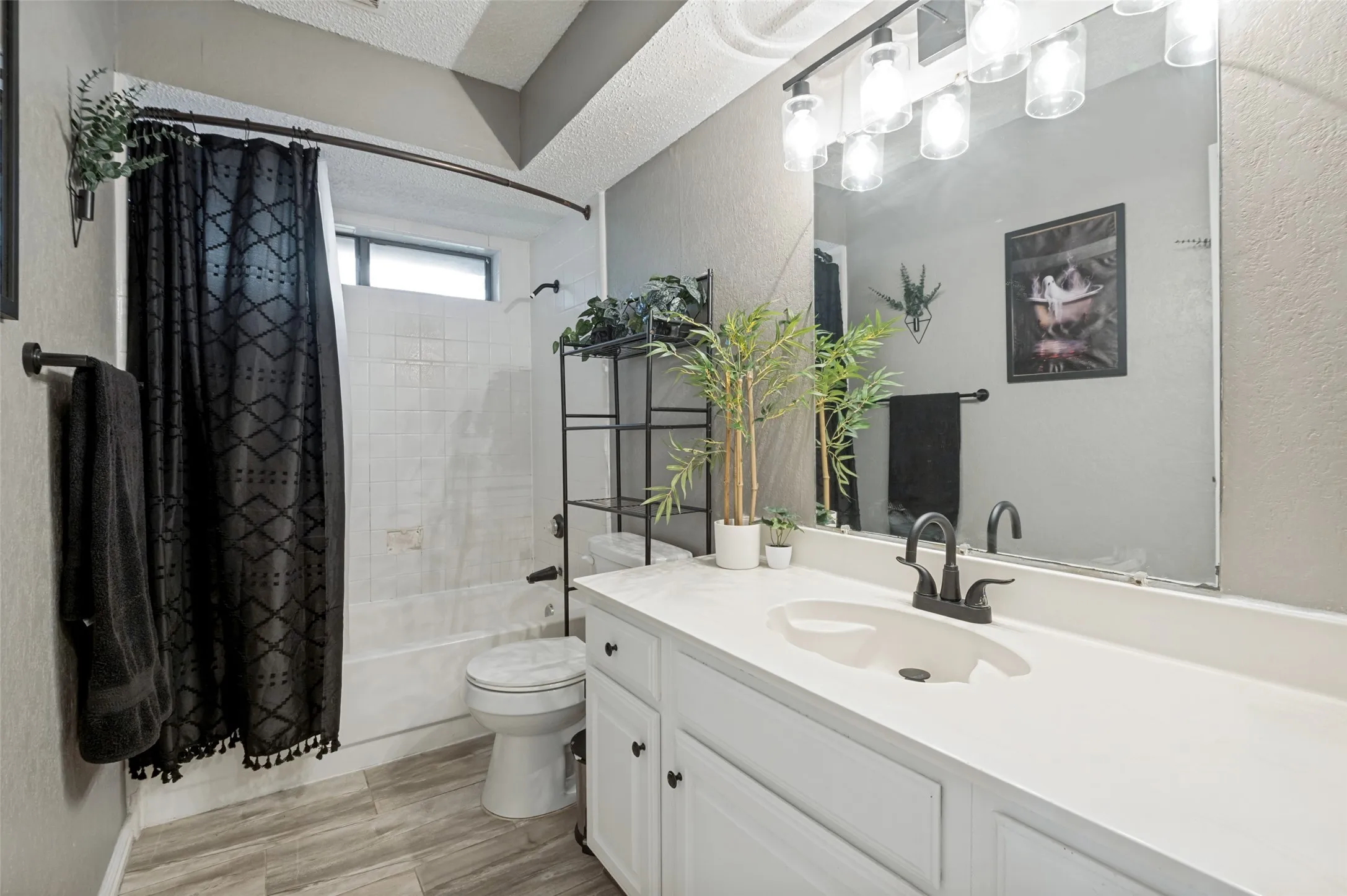 Bathroom featuring a white vanity with integrated sink, matte black faucet, and overhead bar lighting