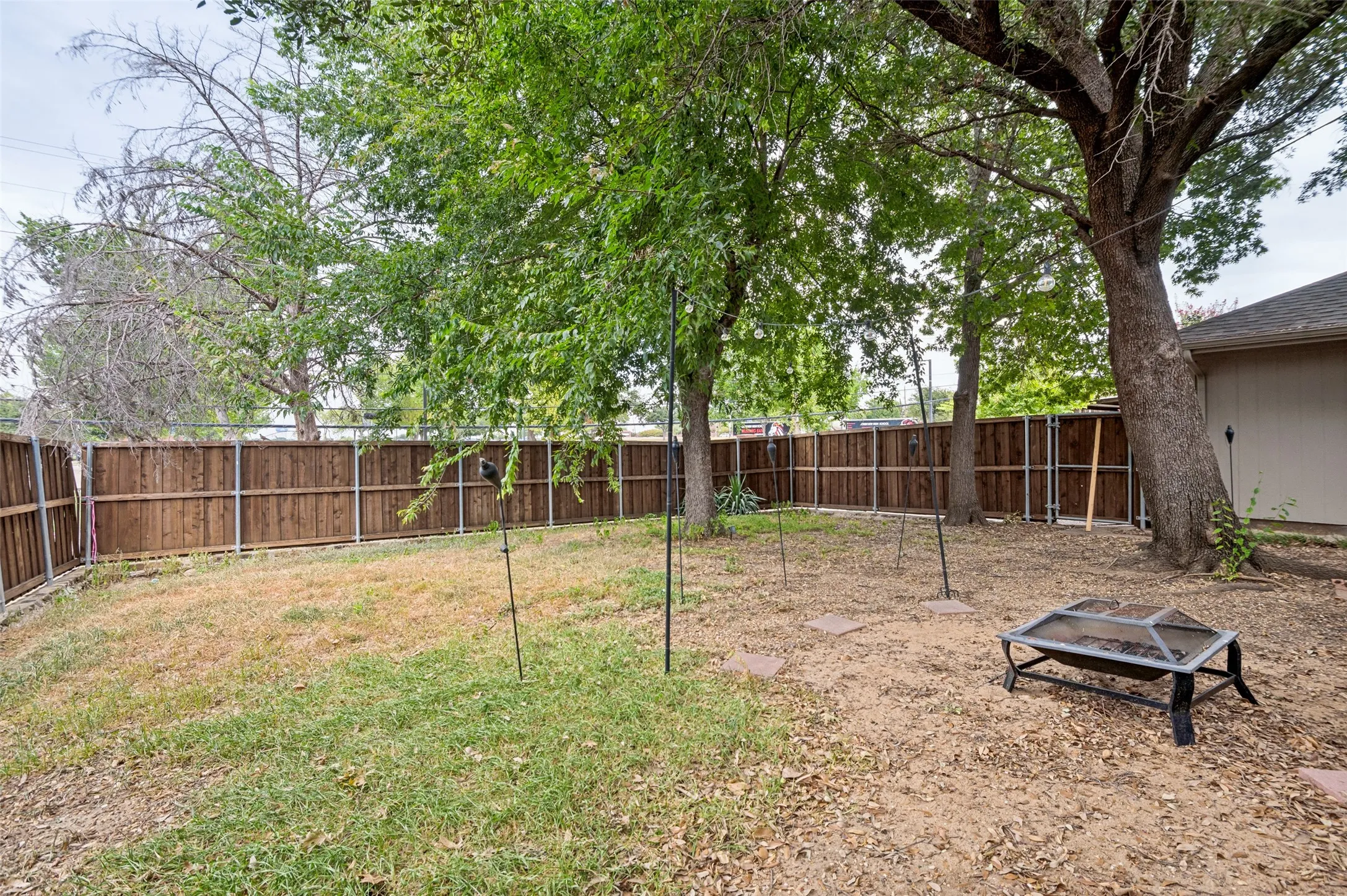 Spacious outdoor area featuring a wood fence and mature trees