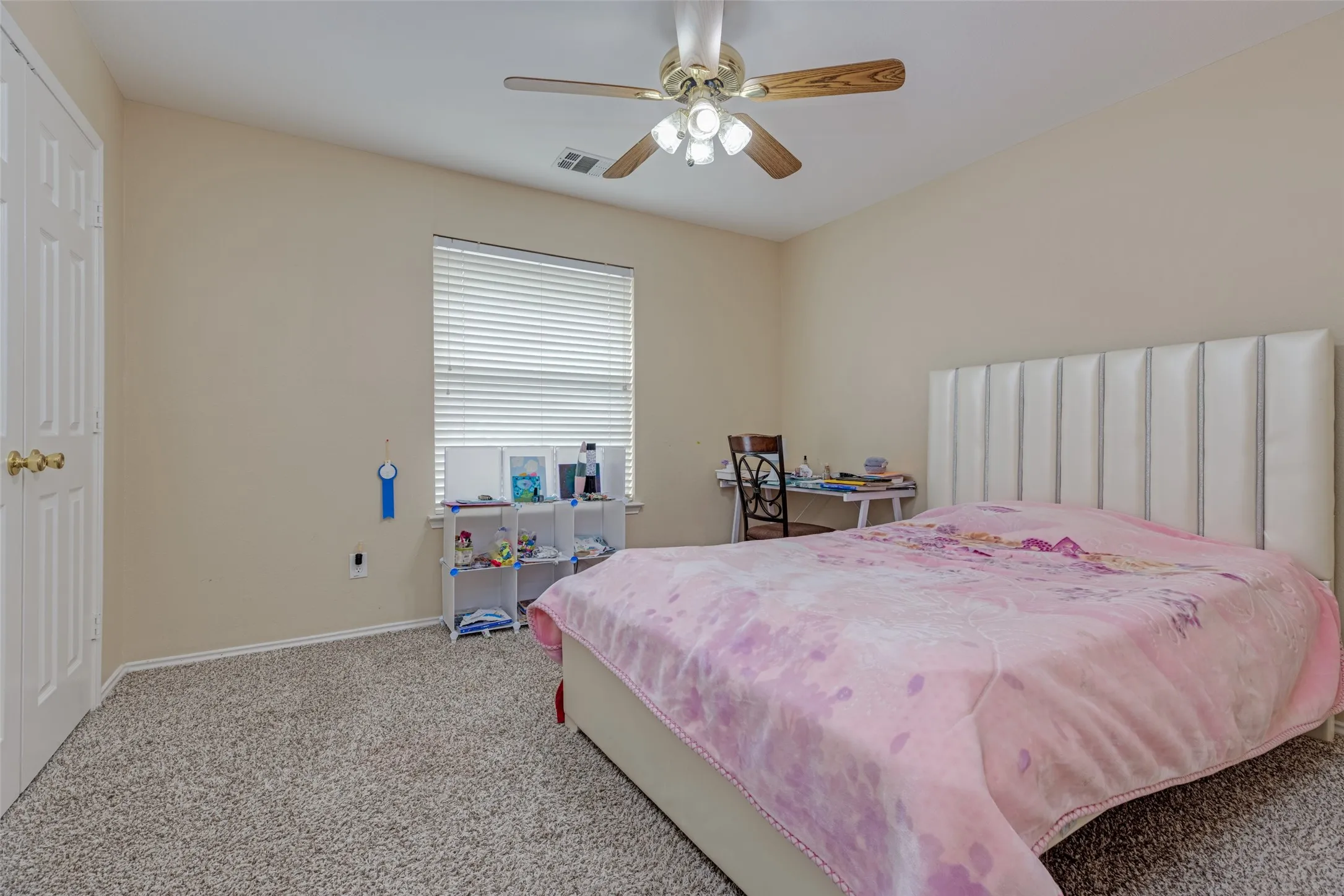 Window with horizontal blinds, textured carpet flooring, ceiling fan with light fixture, and a paneled door