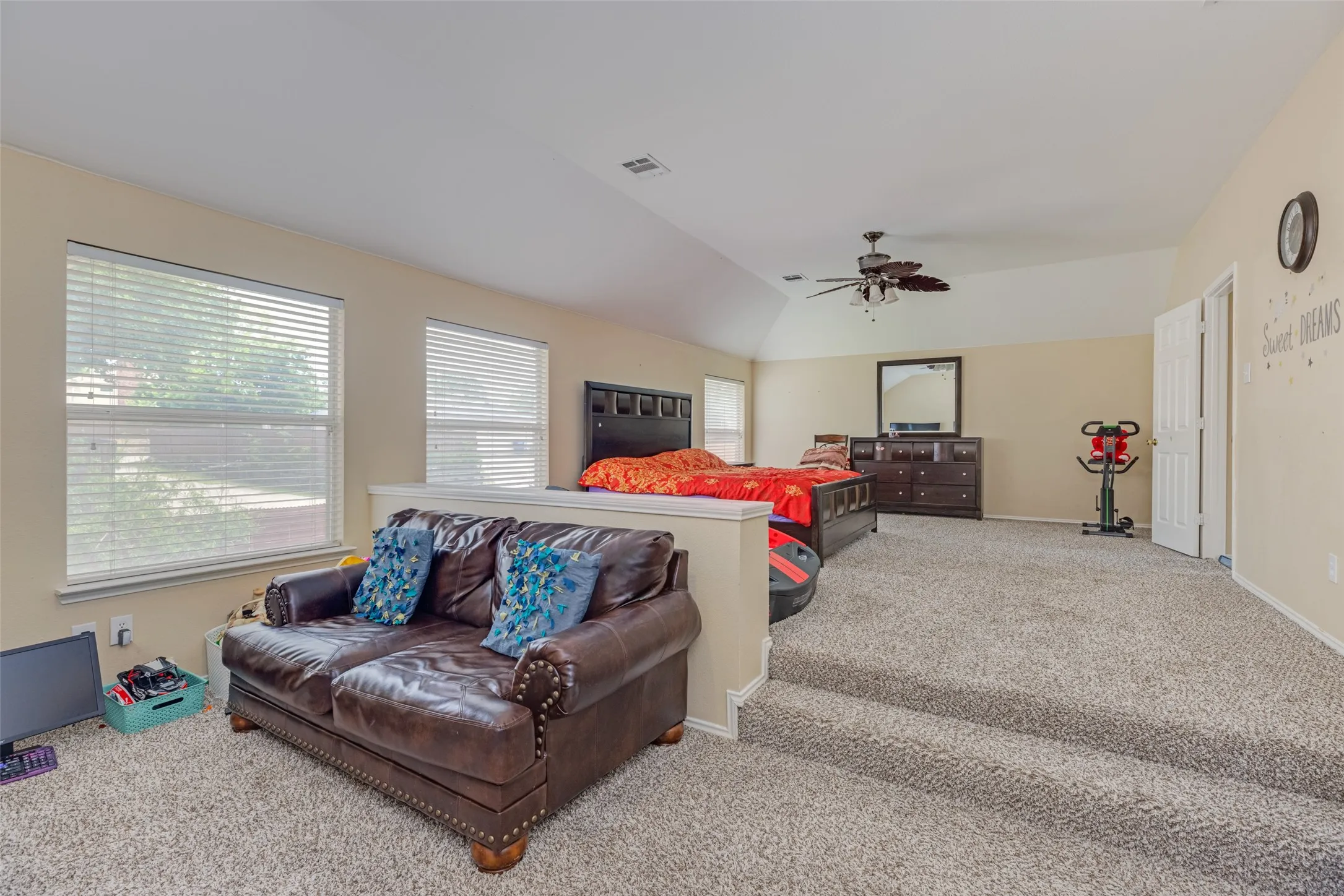 Vaulted ceiling, ceiling fan, two windows with blinds, bi-fold closet doors, and neutral carpet