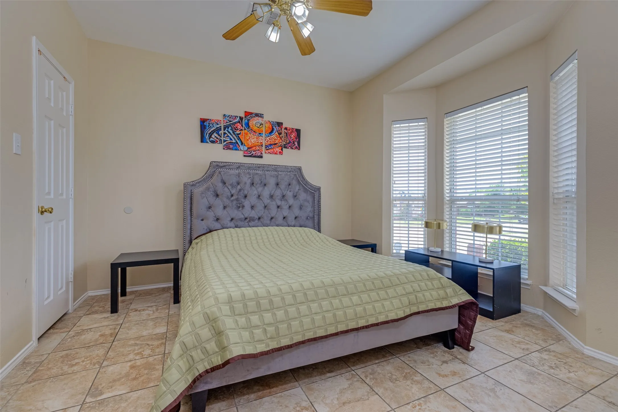 Bay window with multiple windows, ceiling fan with light fixture, and tile flooring