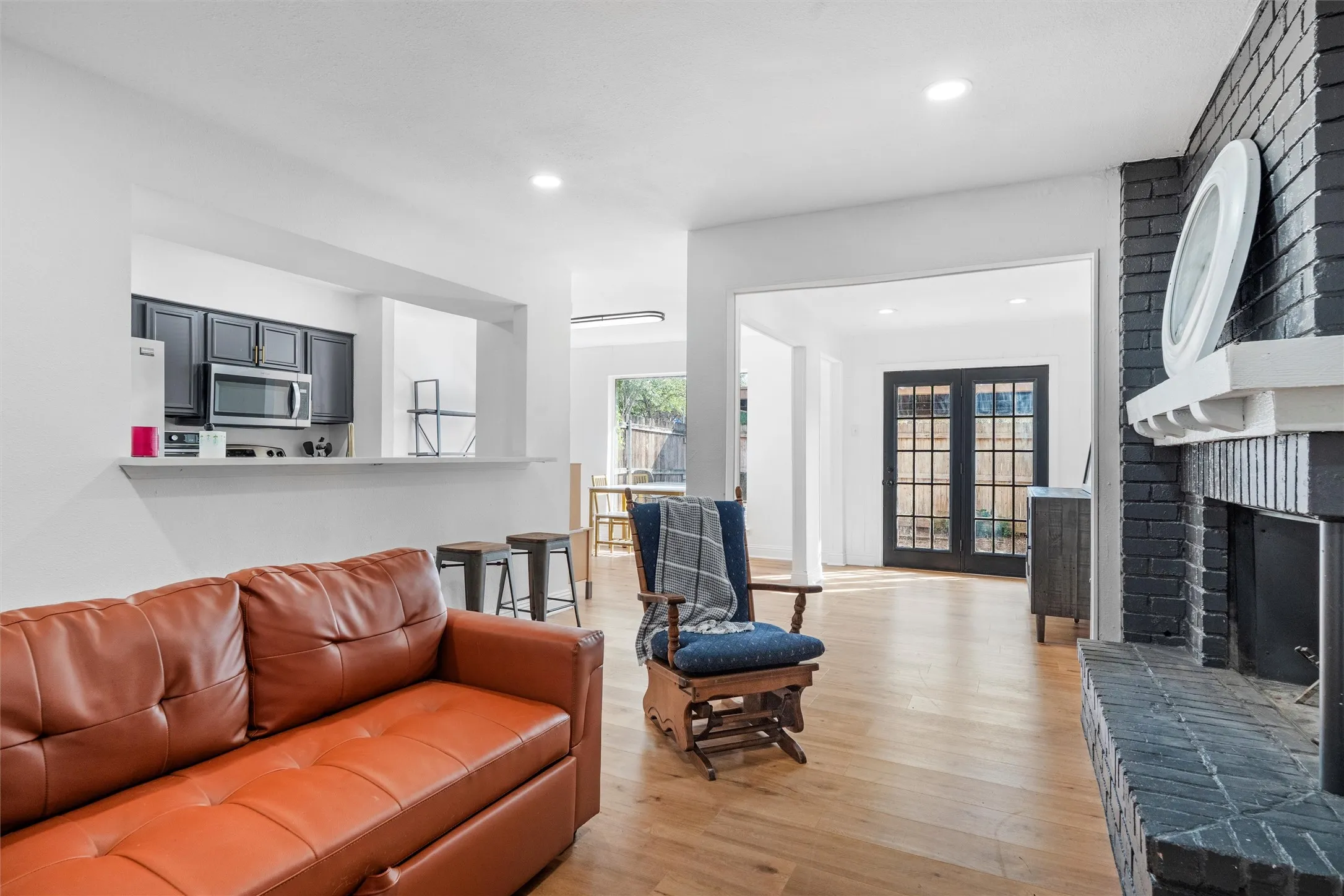 Open-concept living area showcasing hardwood flooring, a leather sectional sofa, and direct access to adjoining spaces through multiple doorways