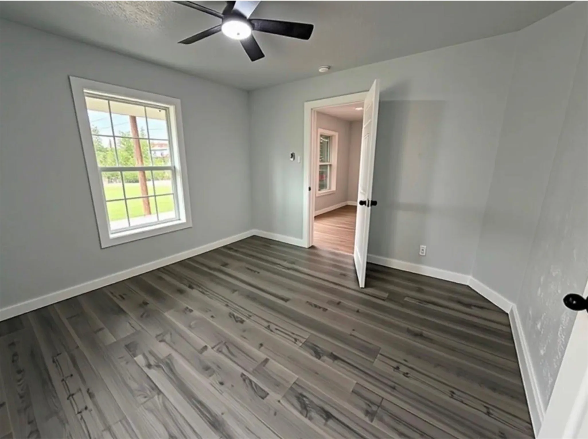 Wood-finish flooring, ceiling fan, and white trim throughout