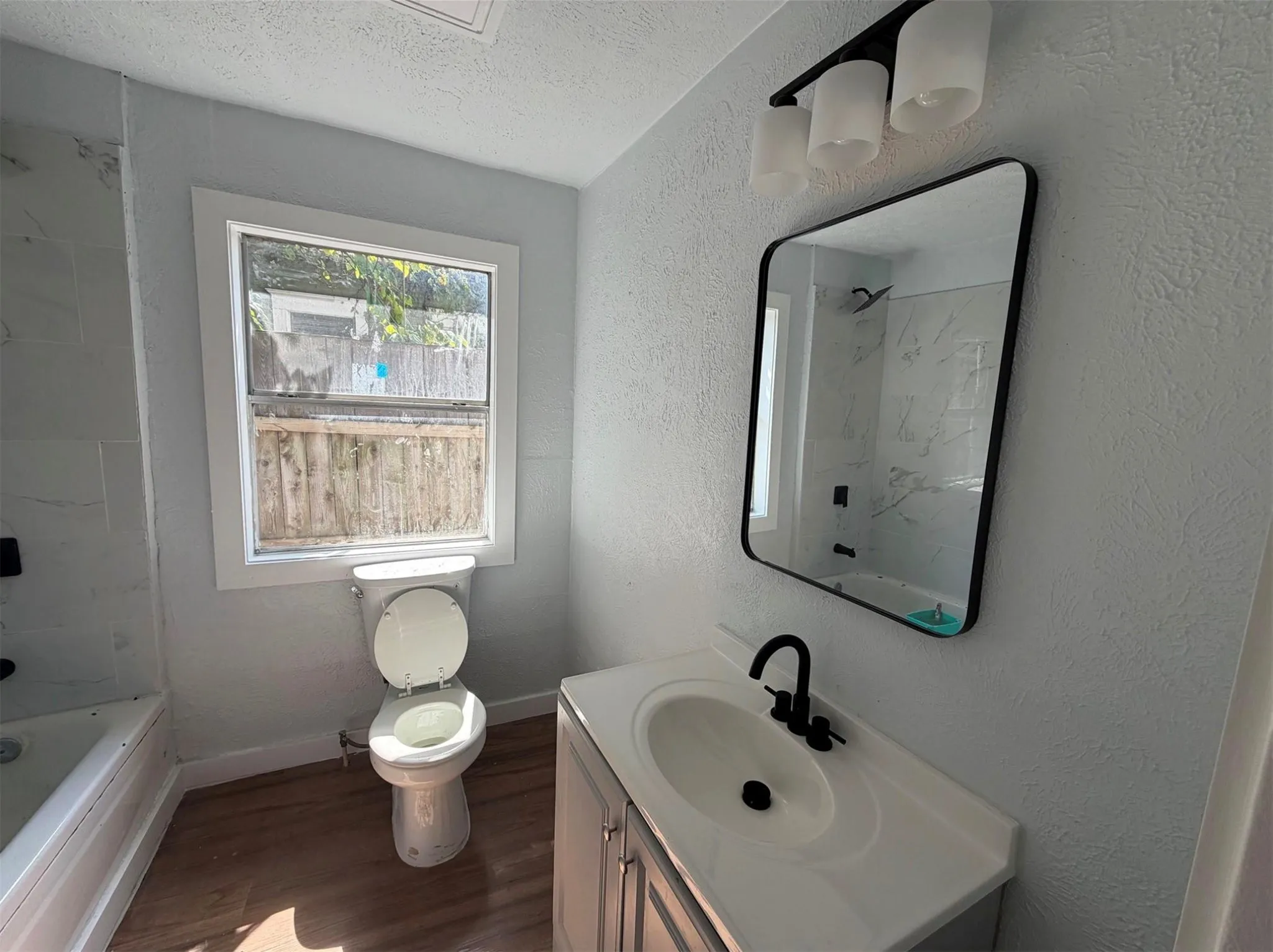 Bathroom featuring a single vanity with dark hardware, recessed sink, and rectangular mirror