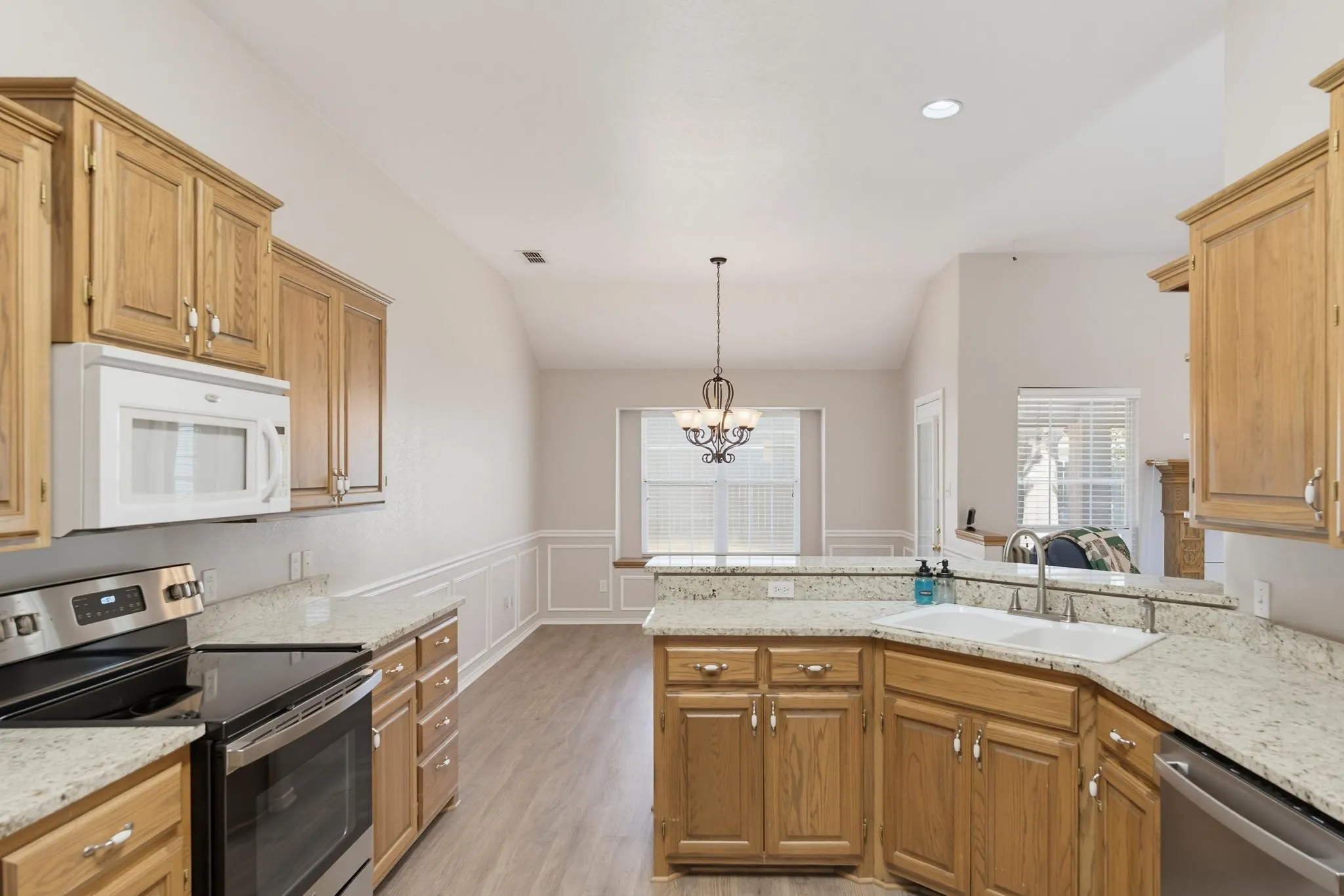 Kitchen featuring light wood cabinetry, light stone countertops, and stainless steel appliances