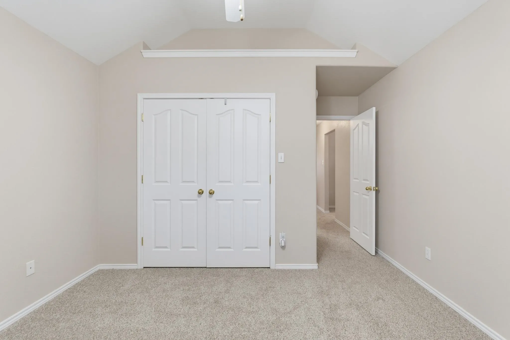 Vaulted ceiling, neutral tone walls, white trim, light tone carpet, and white bi-fold closet doors