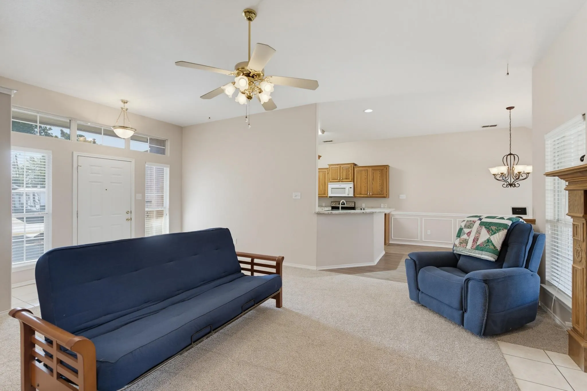 Warm interior featuring a ceiling fan with integrated lighting, a white paneled front door with sidelight windows, and a built-in fireplace with a wood-finish mantel