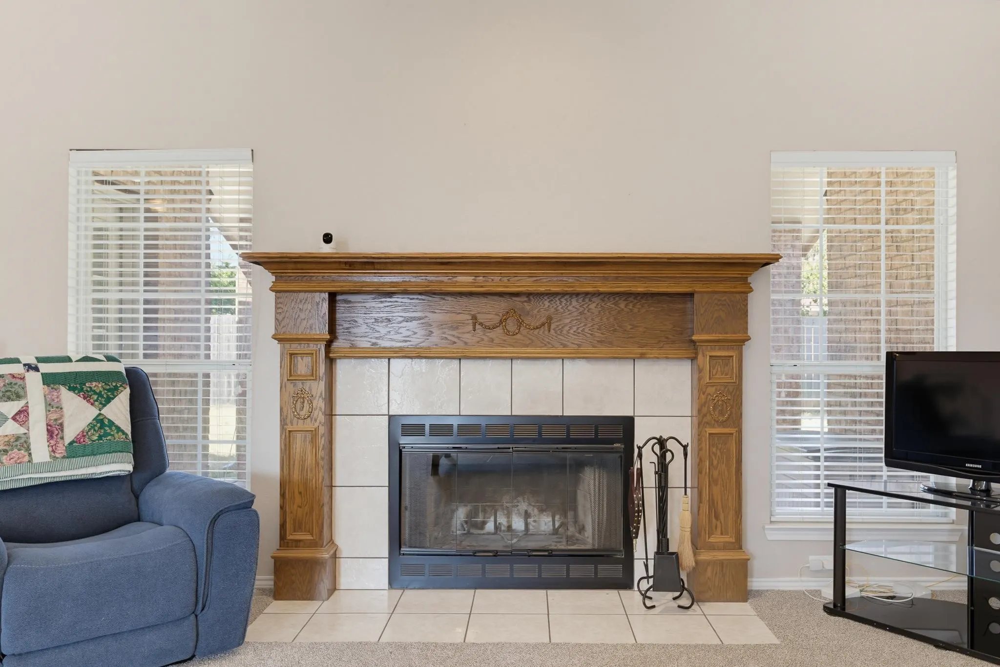 Fireplace featuring a wood mantel with decorative carvings, a tiled surround, and a black firebox