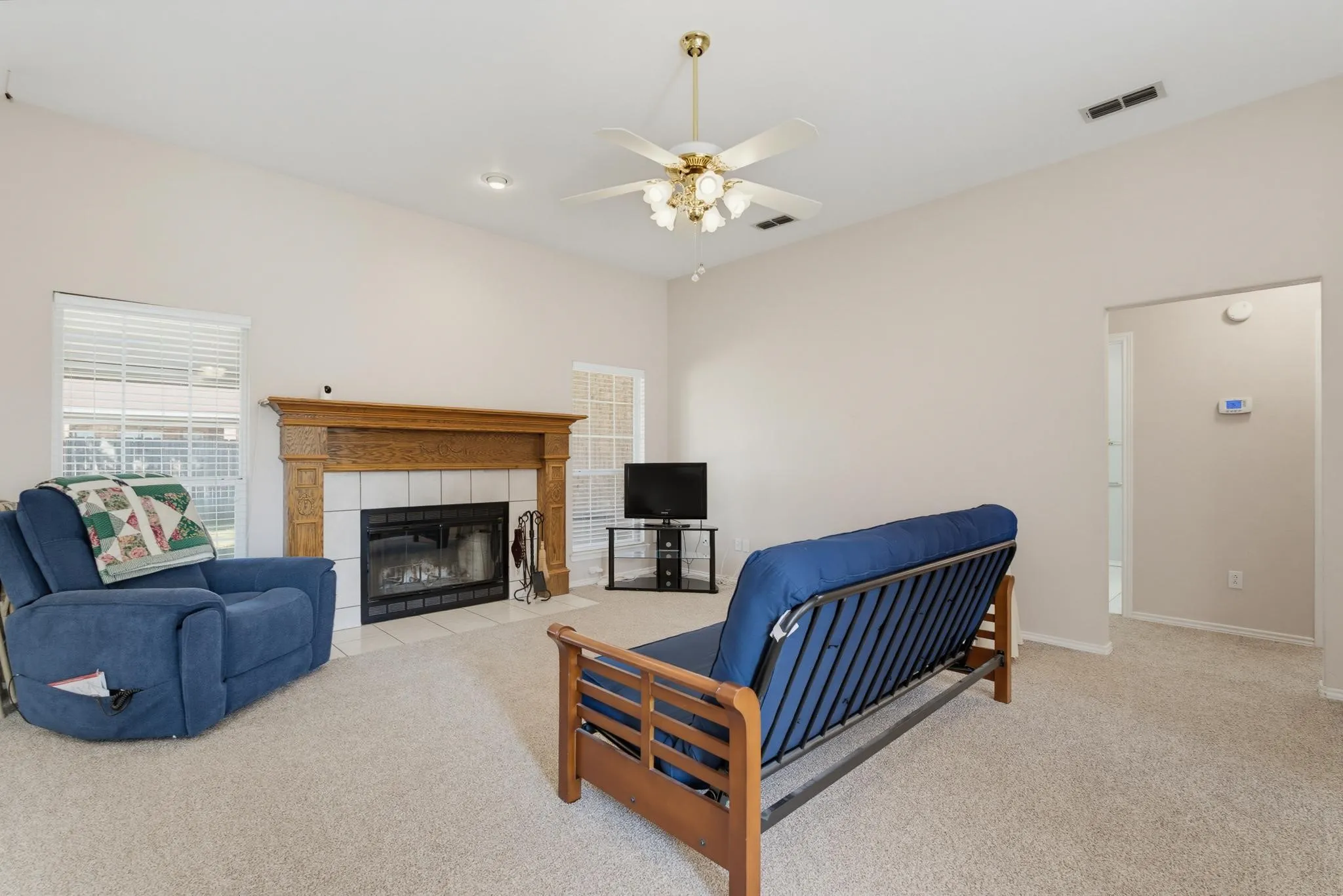 Vaulted ceiling, ceiling fan with integrated lighting, wood-finish fireplace mantel, tiled fireplace surround, and recessed lighting