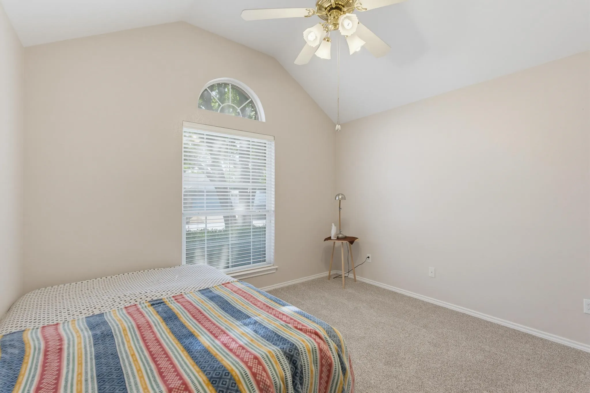 Vaulted ceilings with an arched window, a full-size window with blinds, and carpet flooring