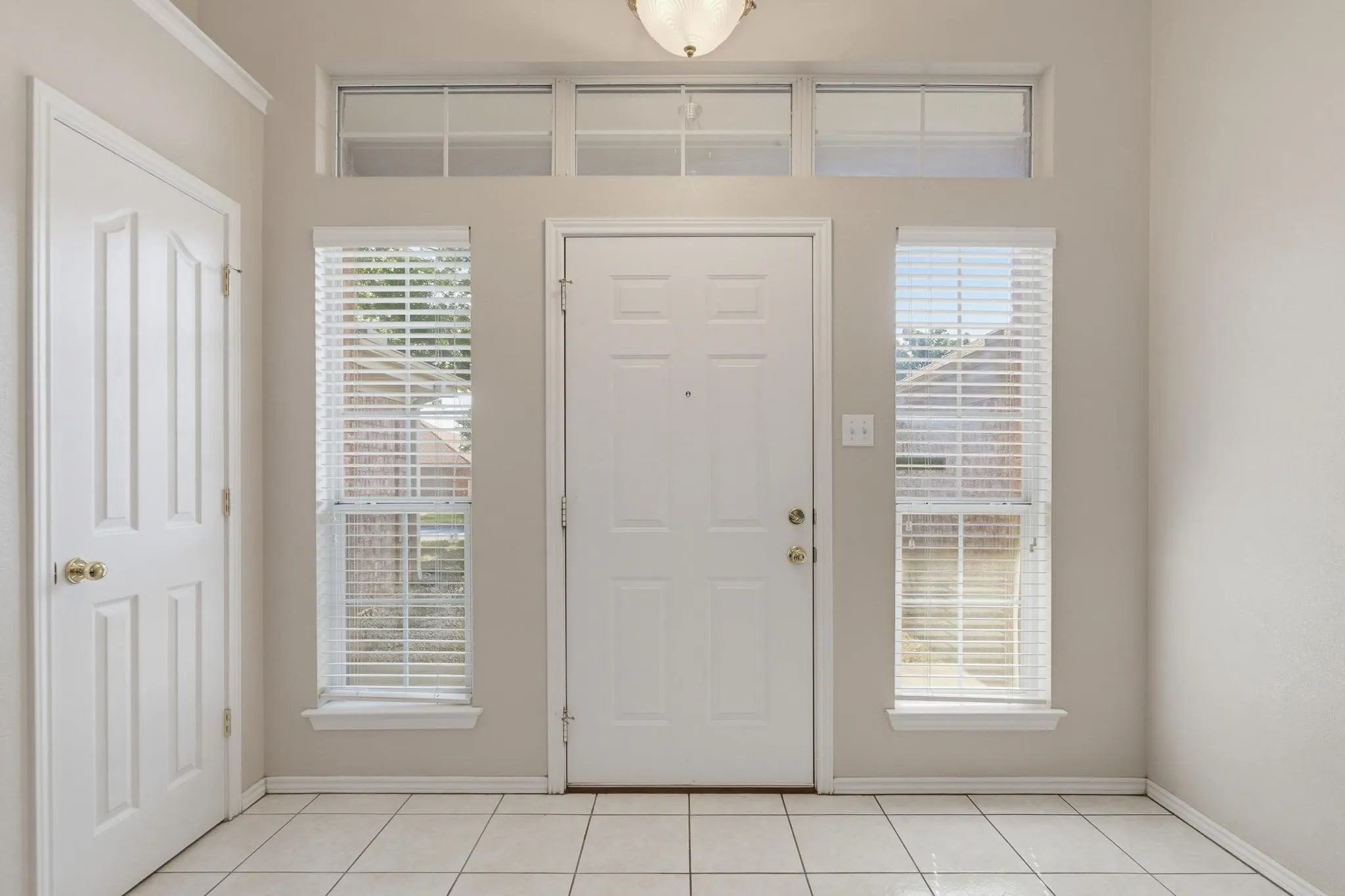 Entryway featuring a panel door, transom window, and tiled flooring