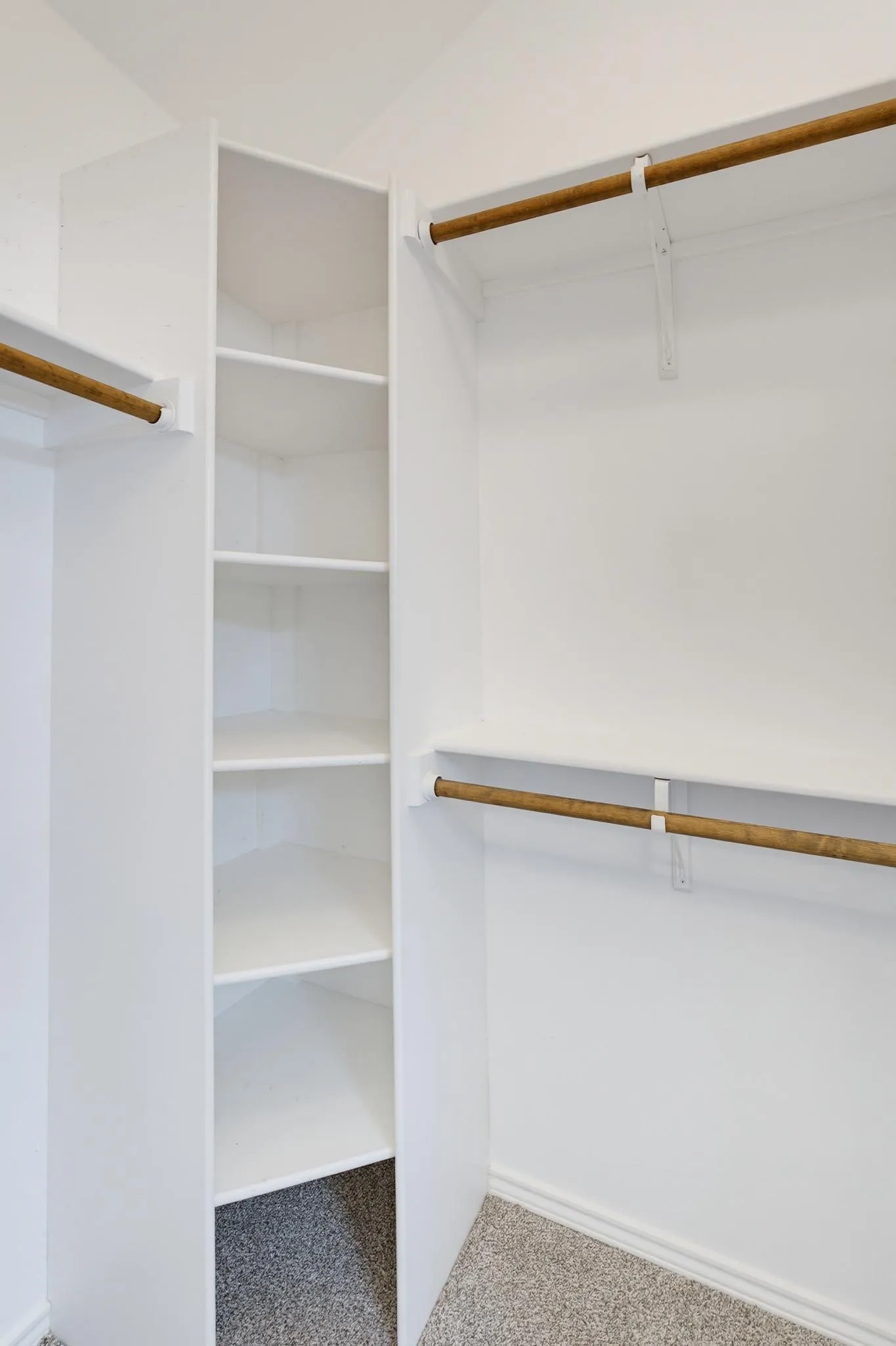 Built-in closet shelving system with multiple storage racks and hanging rods, complemented by carpet flooring