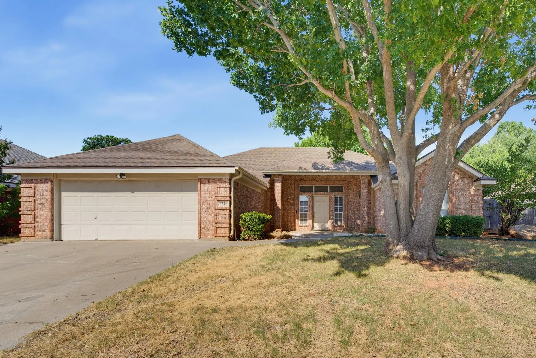 Brick exterior with a peaked roofline, attached two-car garage, and a concrete driveway