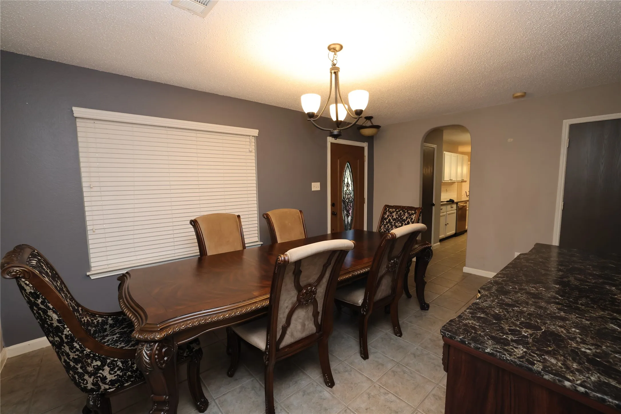 Recessed ceiling lighting, a decorative chandelier, and an arched doorway