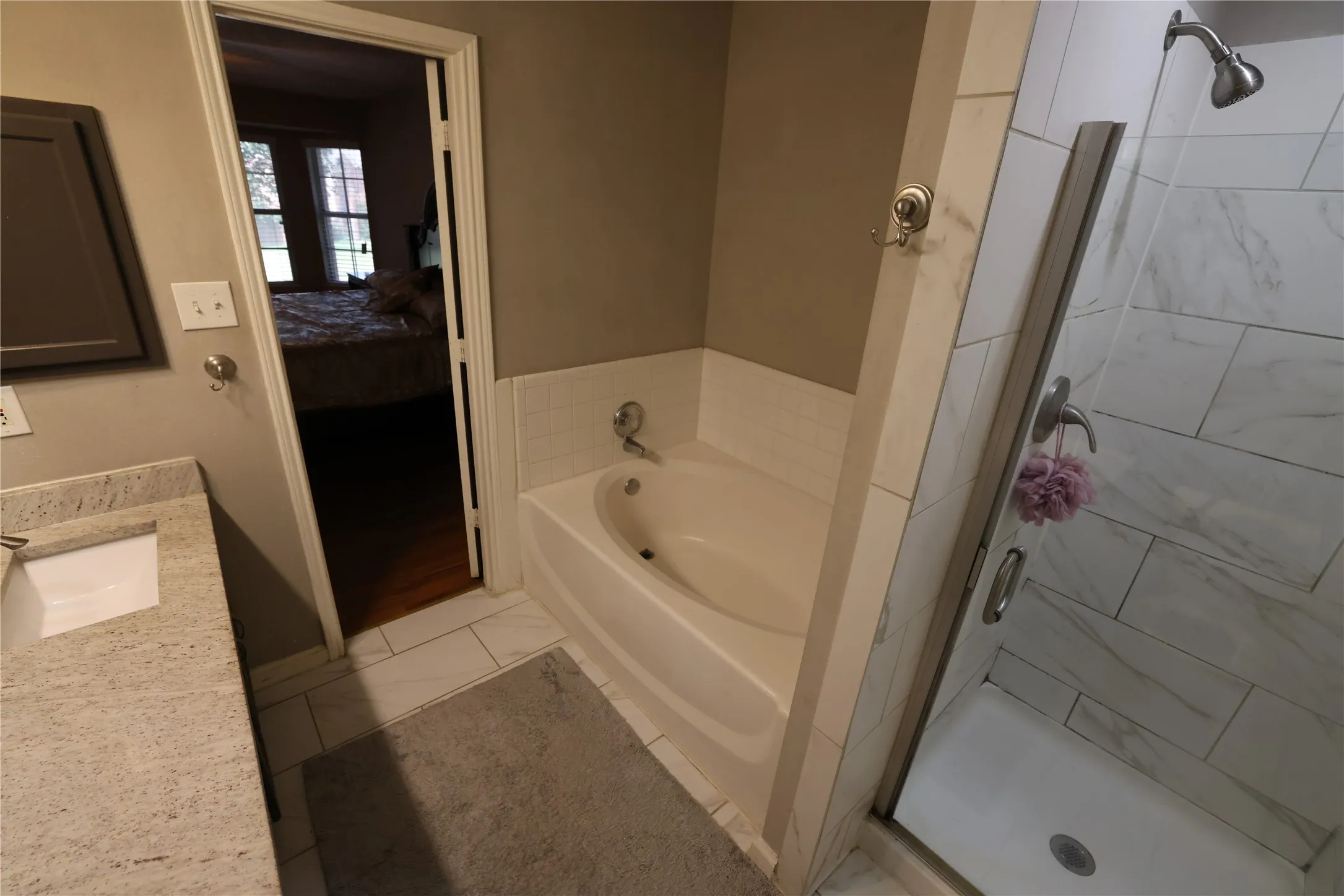 Bathtub with tile surround, walk-in shower with clear glass enclosure and tile walls, and a vanity with an integrated sink and light-toned countertop