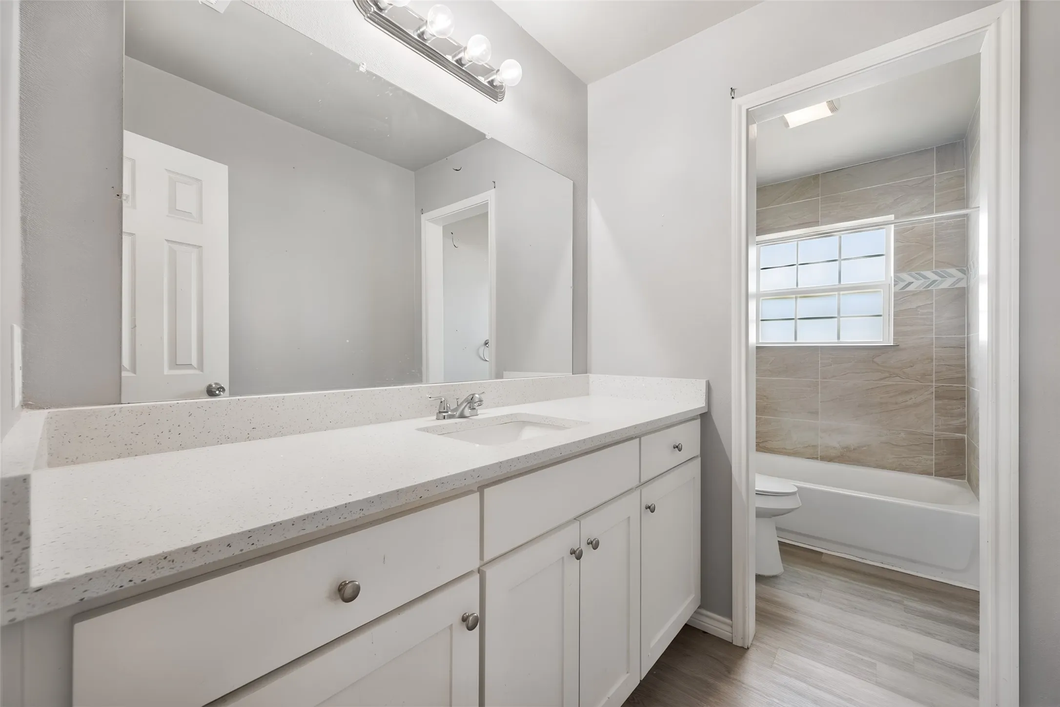 Dual-sink vanity with white cabinetry, light-colored countertop, and a large mirror
