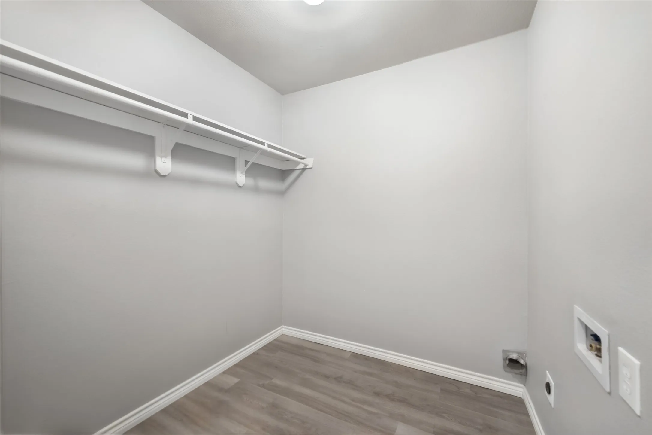 Dedicated utility space featuring a neutral color palette, wood-finish flooring, and integrated shelving