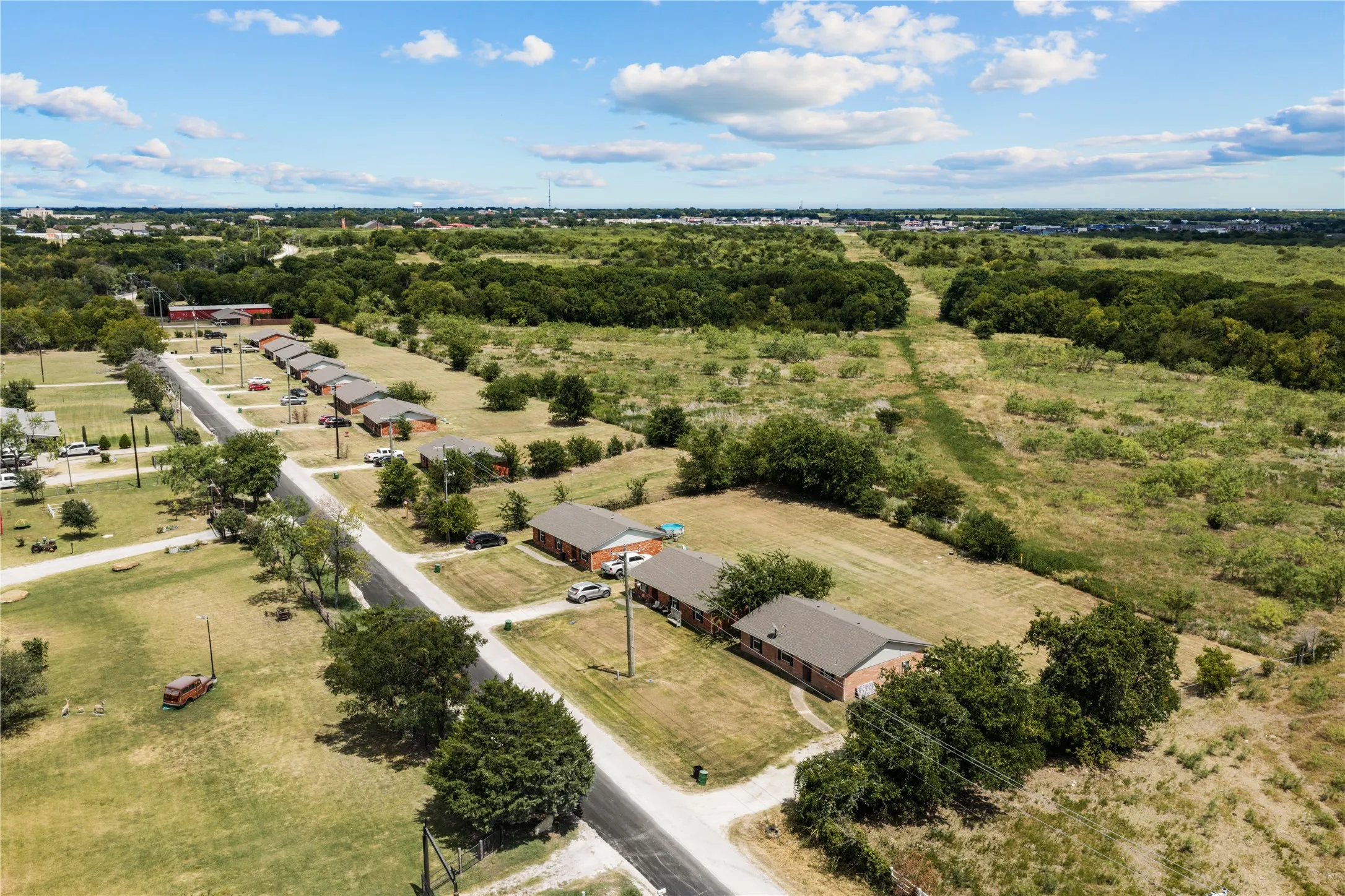 Aerial perspective showcasing multiple residential structures with brick exteriors and shingle roofs, situated along paved roads