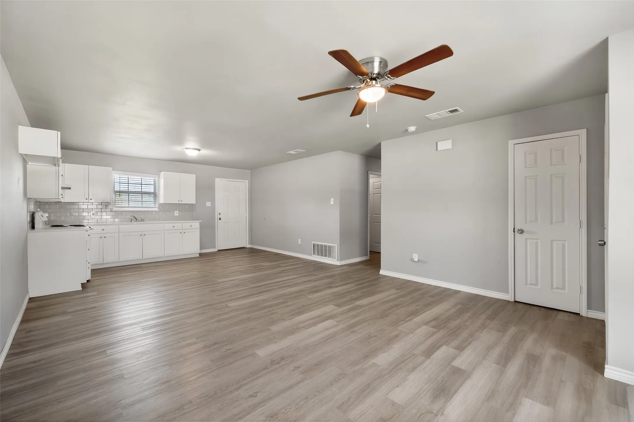 Open-concept living area with wood-finish flooring, a ceiling fan, and recessed lighting
